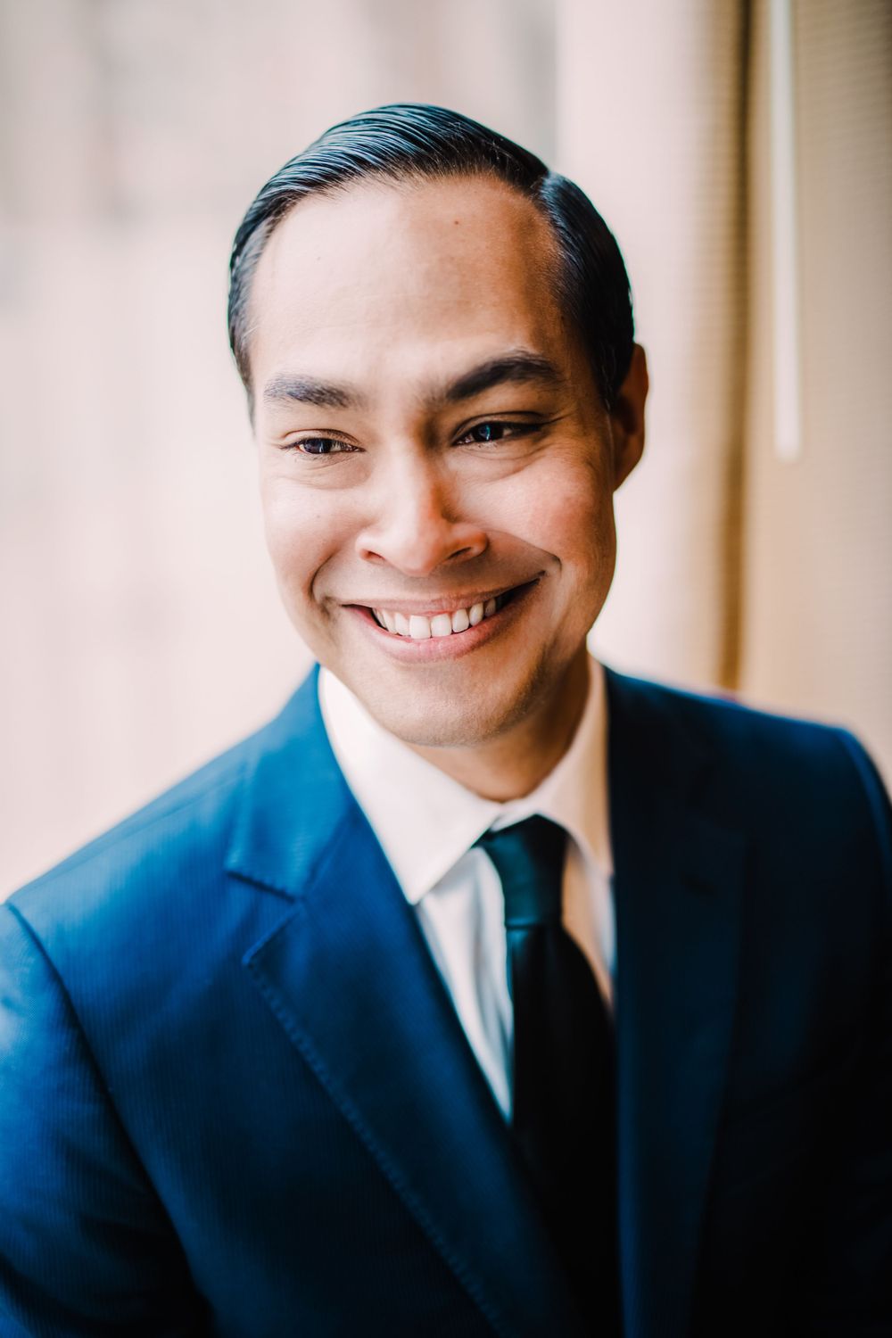 A person in a blue suit and tie smiles warmly in a professional headshot.