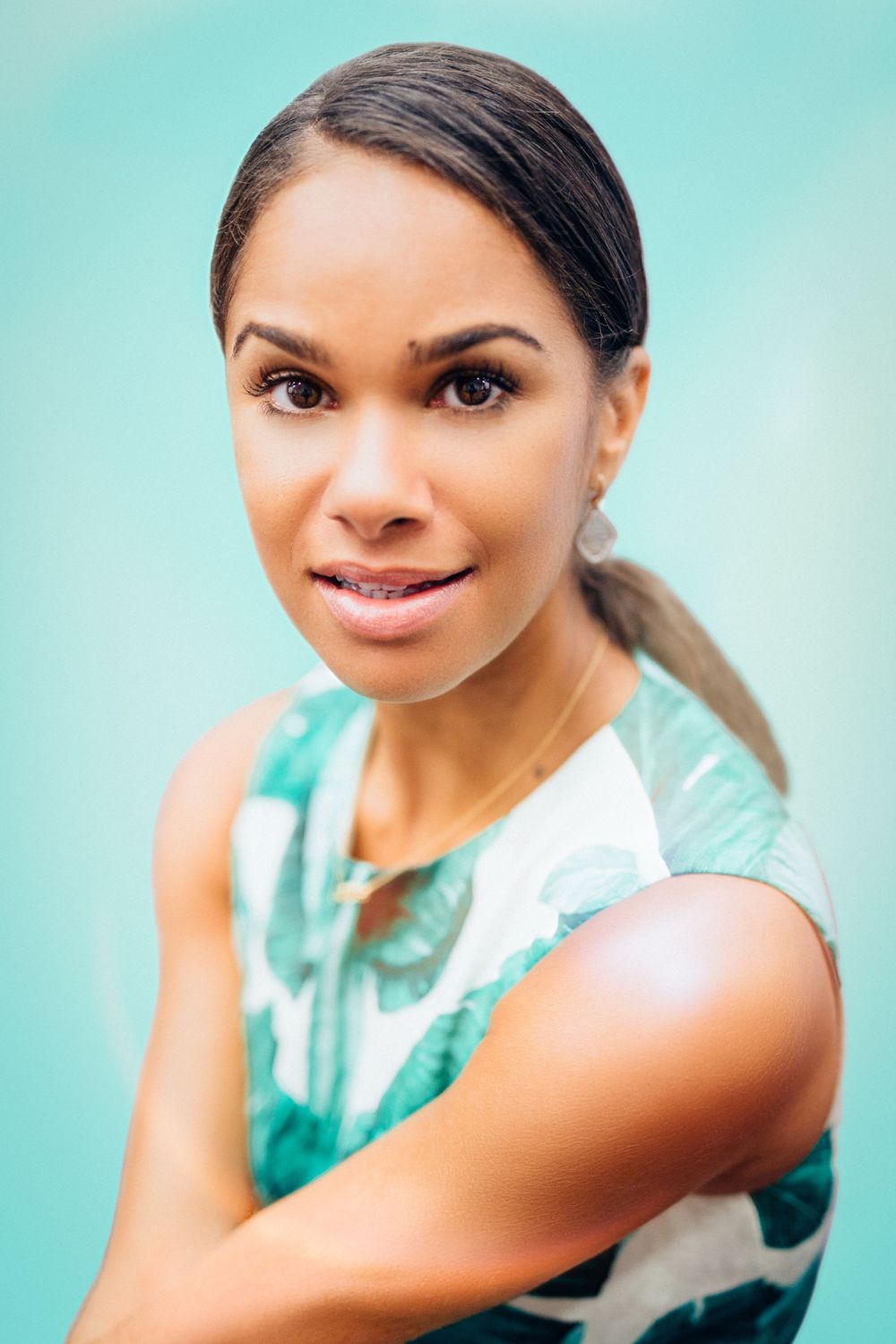 Misty Copeland. A woman in a turquoise sleeveless top poses against a matching aqua background.