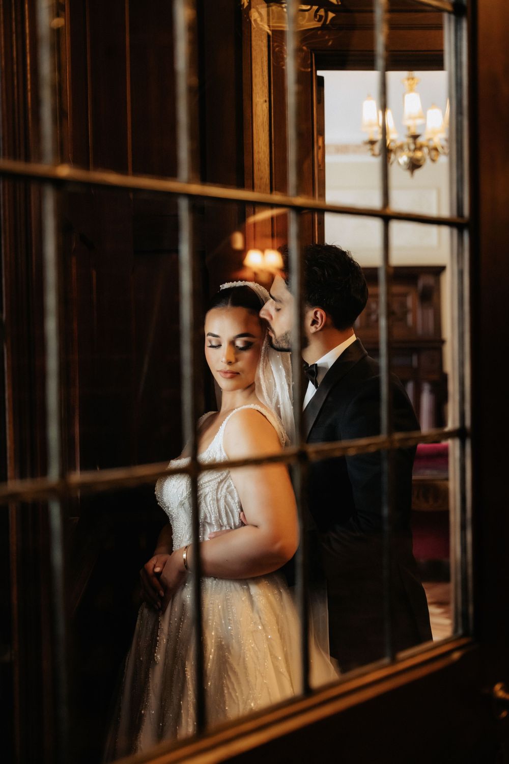 Artistic window reflection shot of formal couple in vintage interior setting.