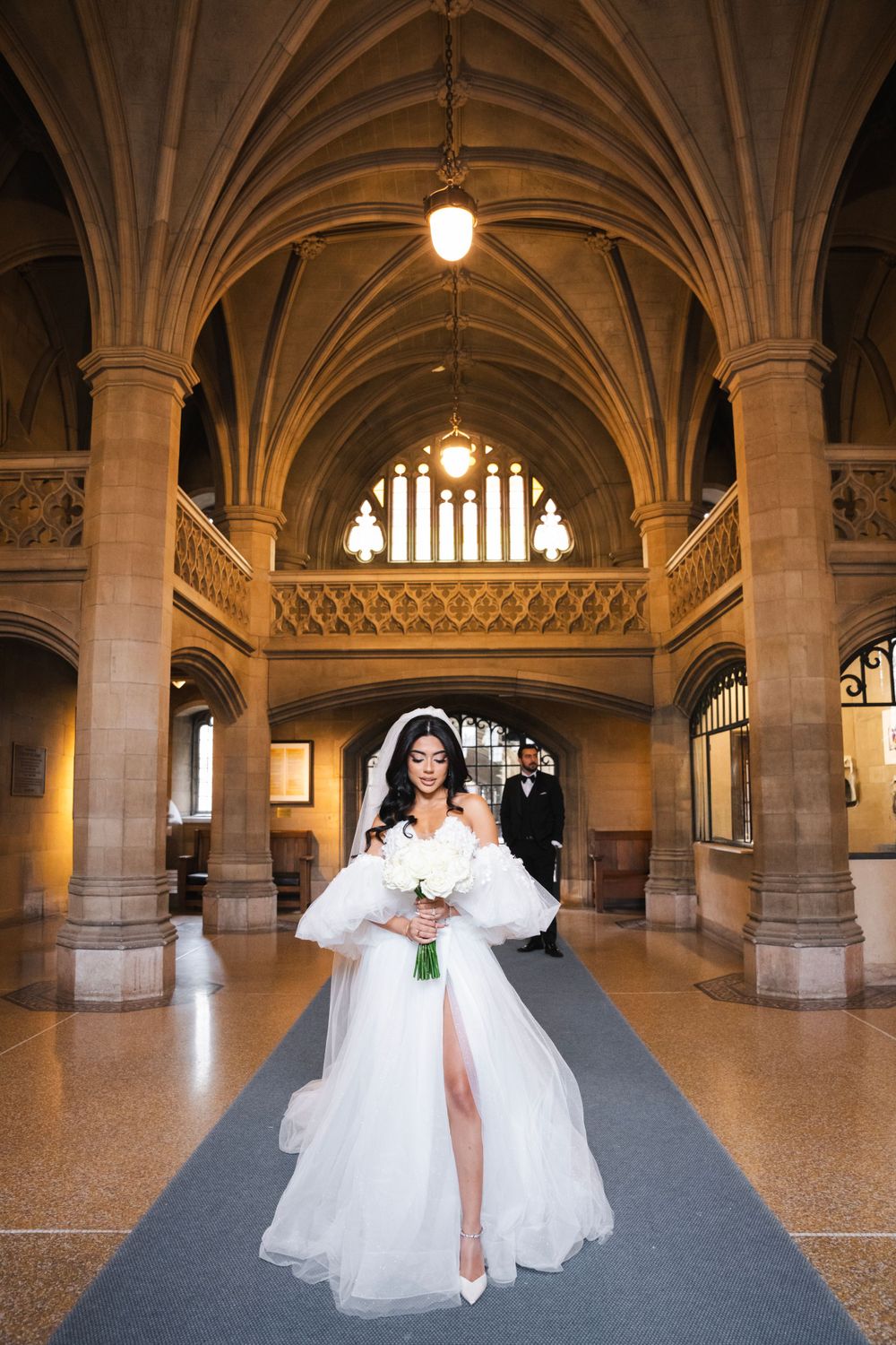 Wedding photo in gothic cathedral hallway featuring dramatic vaulted ceiling and arches.