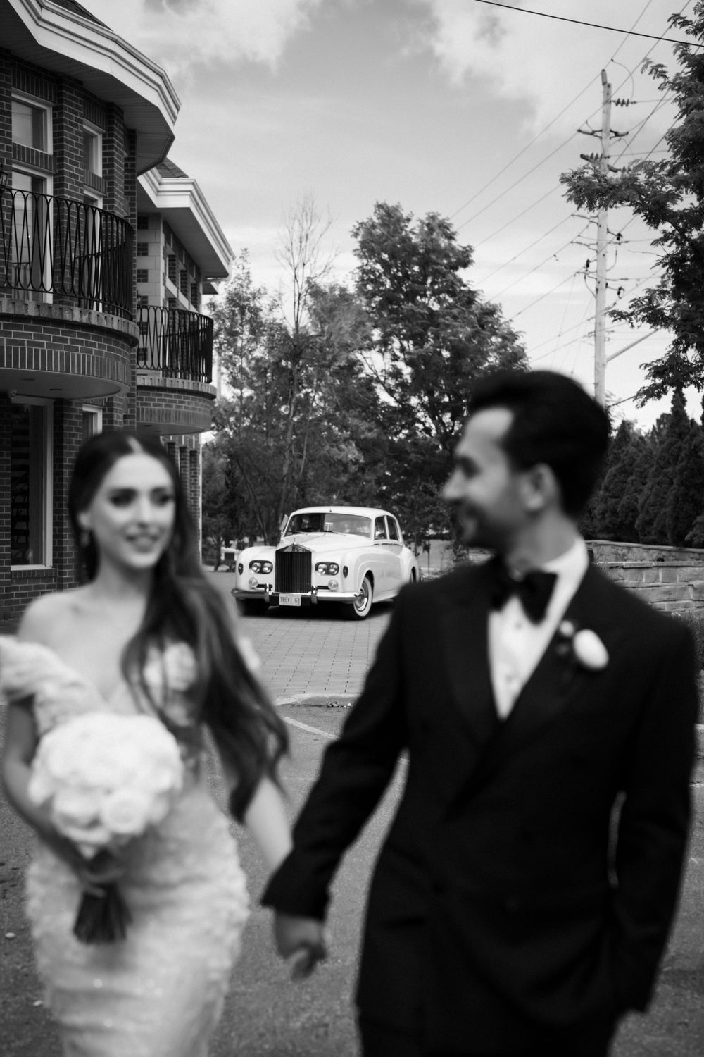 Black and white wedding photography series showing a playful couple on a residential street.