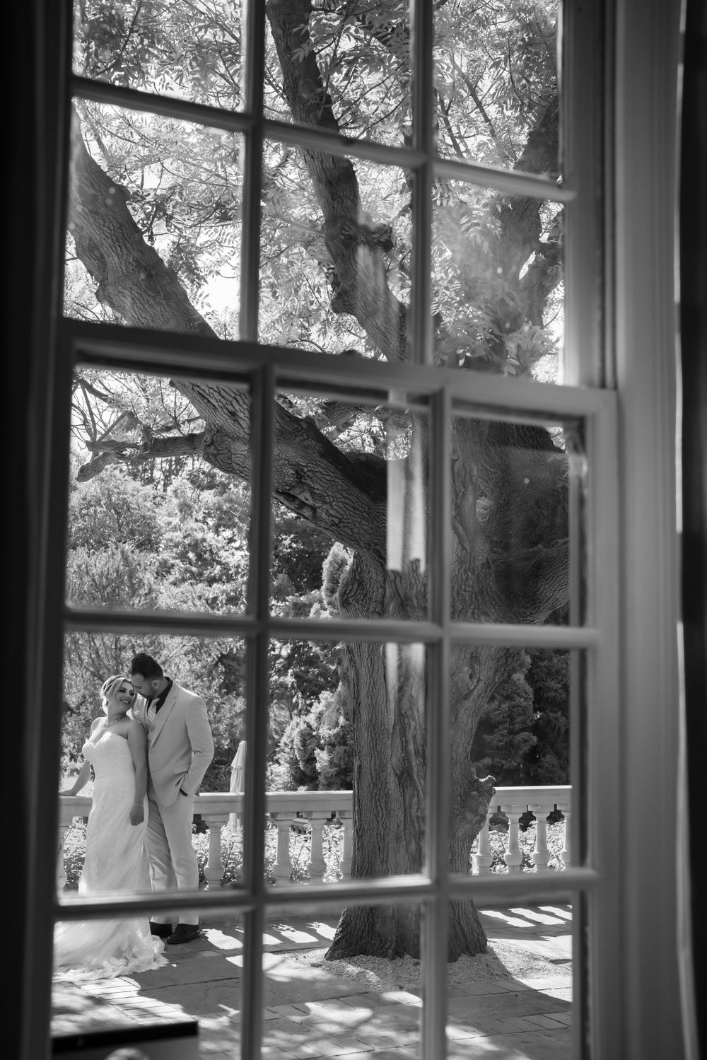 Wedding couple viewed through window panes in elegant venue creating romantic framed composition.