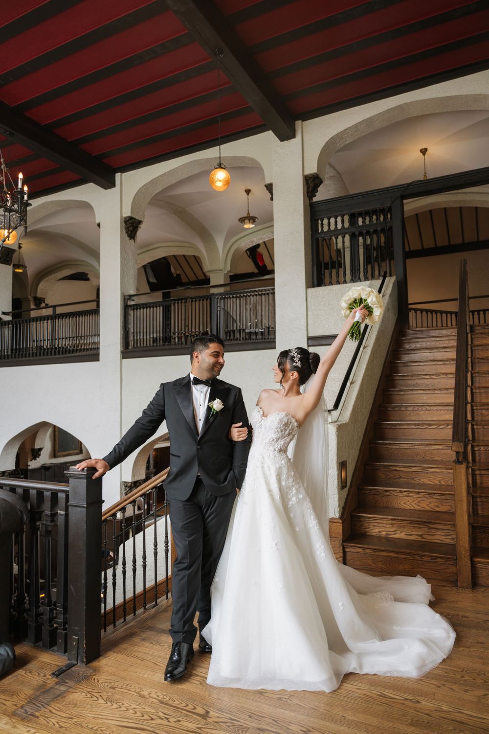 An elegant indoor venue with wooden beams and white archways creates a classic wedding setting.