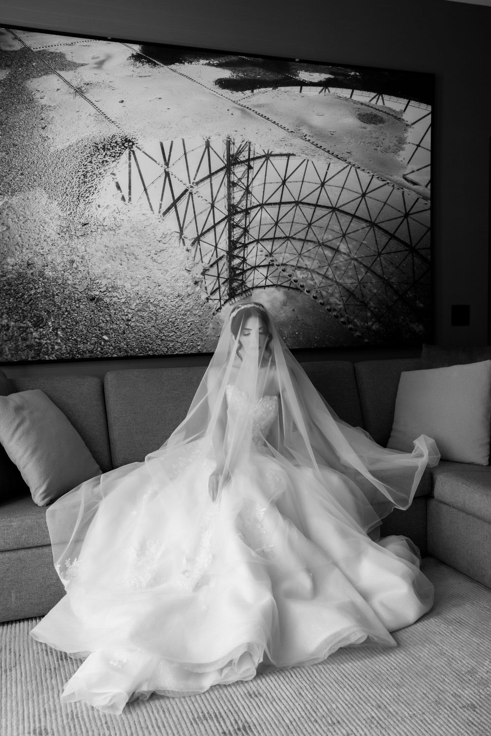 Dramatic black and white bridal portrait on couch with architectural artwork above.