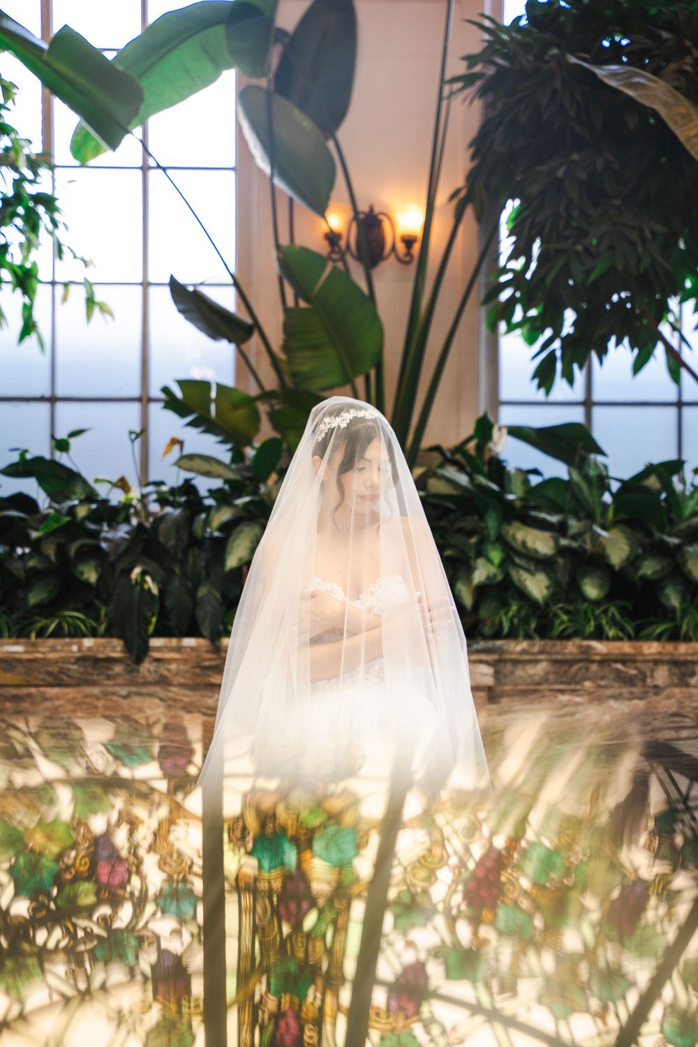 Ethereal bridal portraits under indoor greenhouse lighting with tropical plants and twinkling lights.