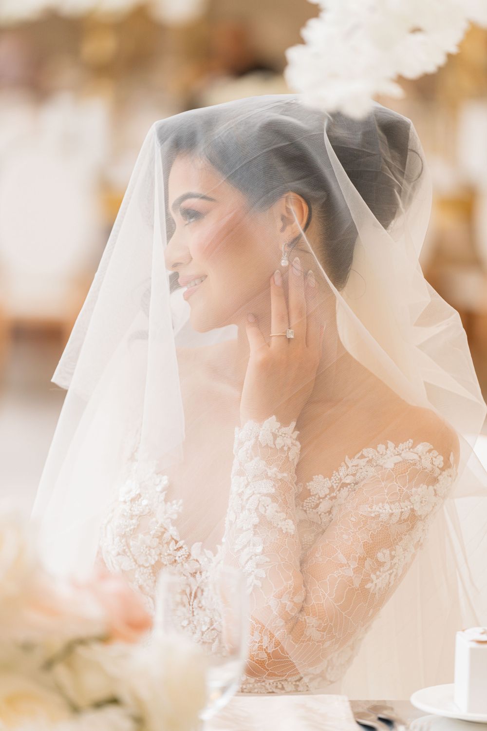 Ethereal bridal portrait through delicate lace veil in soft, romantic lighting.