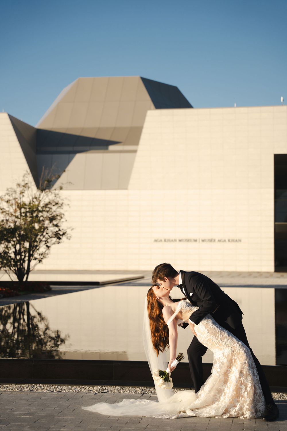 Wedding couple sharing intimate moment against modern museum architecture.