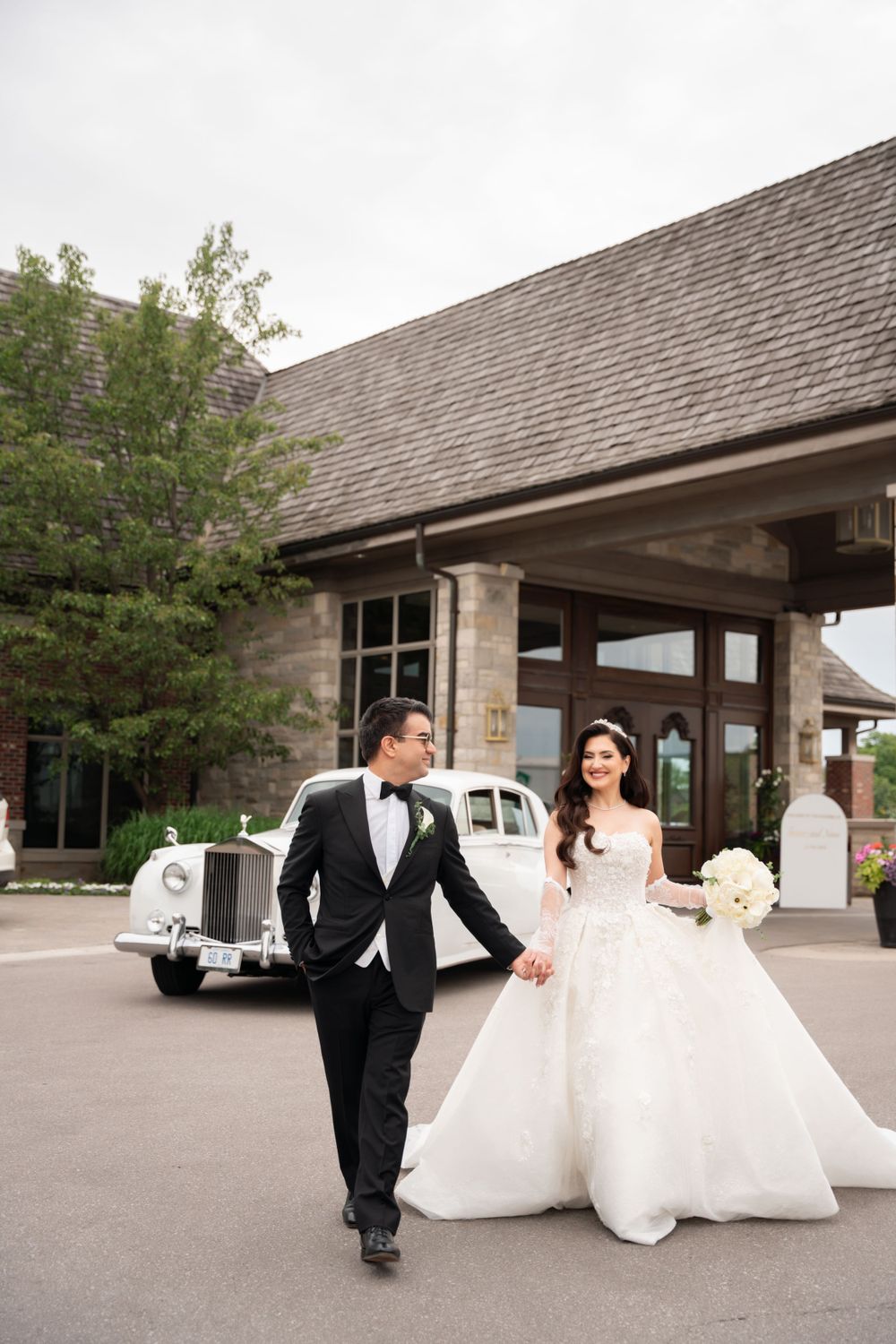 Playful wedding couple runs and poses outside stone building entrance.