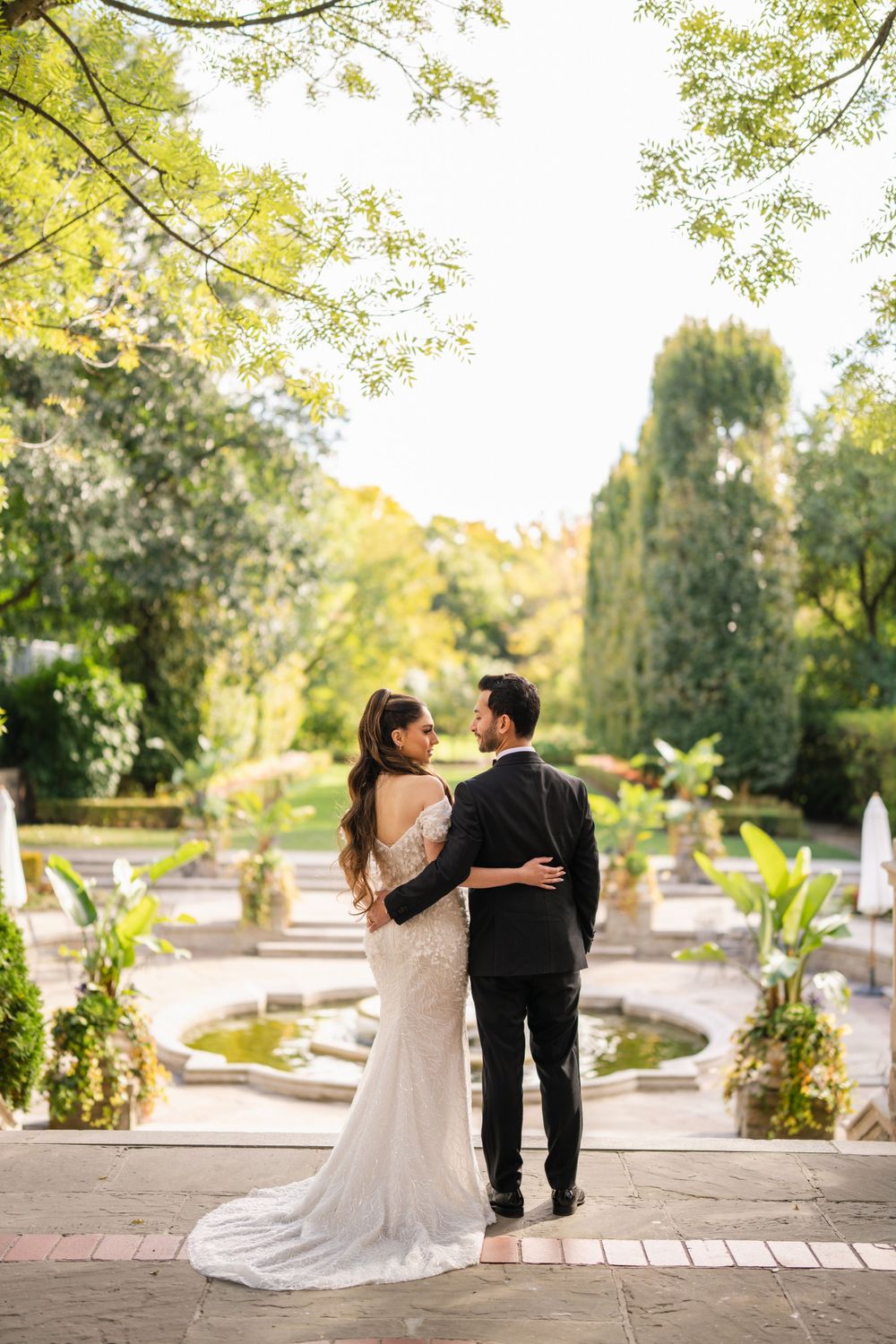 A romantic garden path photoshoot featuring a couple strolling amid lush greenery and stone architecture.