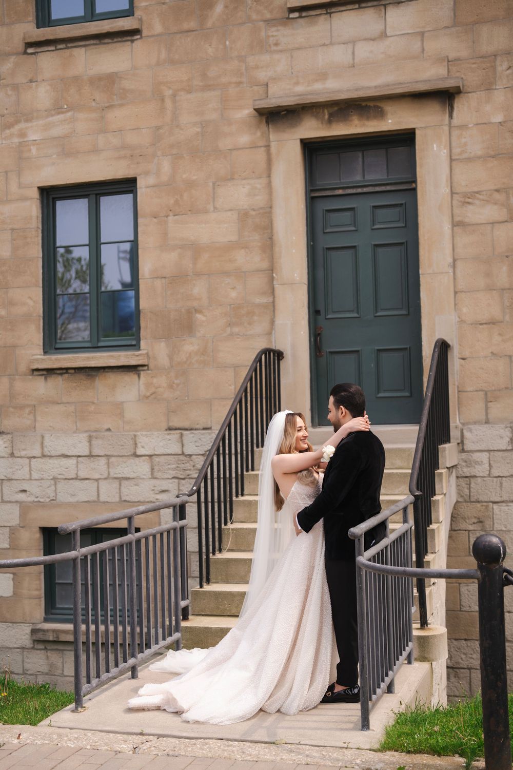 Romantic wedding portrait of couple on stone steps with vintage architecture backdrop.