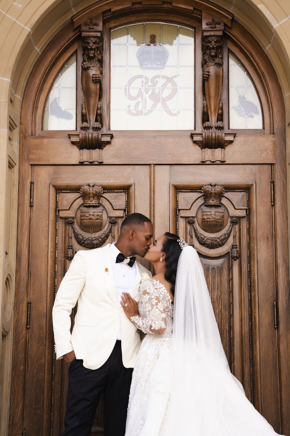 Wedding couple sharing intimate moments in front of ornate wooden church doors.