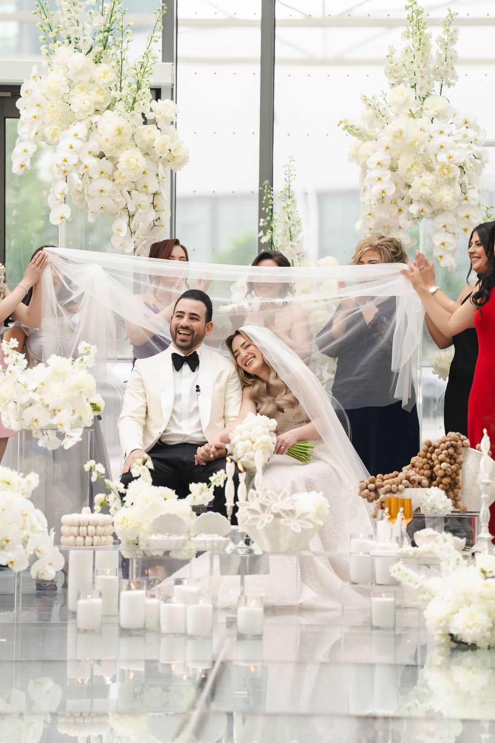 Elegant wedding reception featuring white floral arrangements with newlyweds and guests enjoying a candlelit celebration.