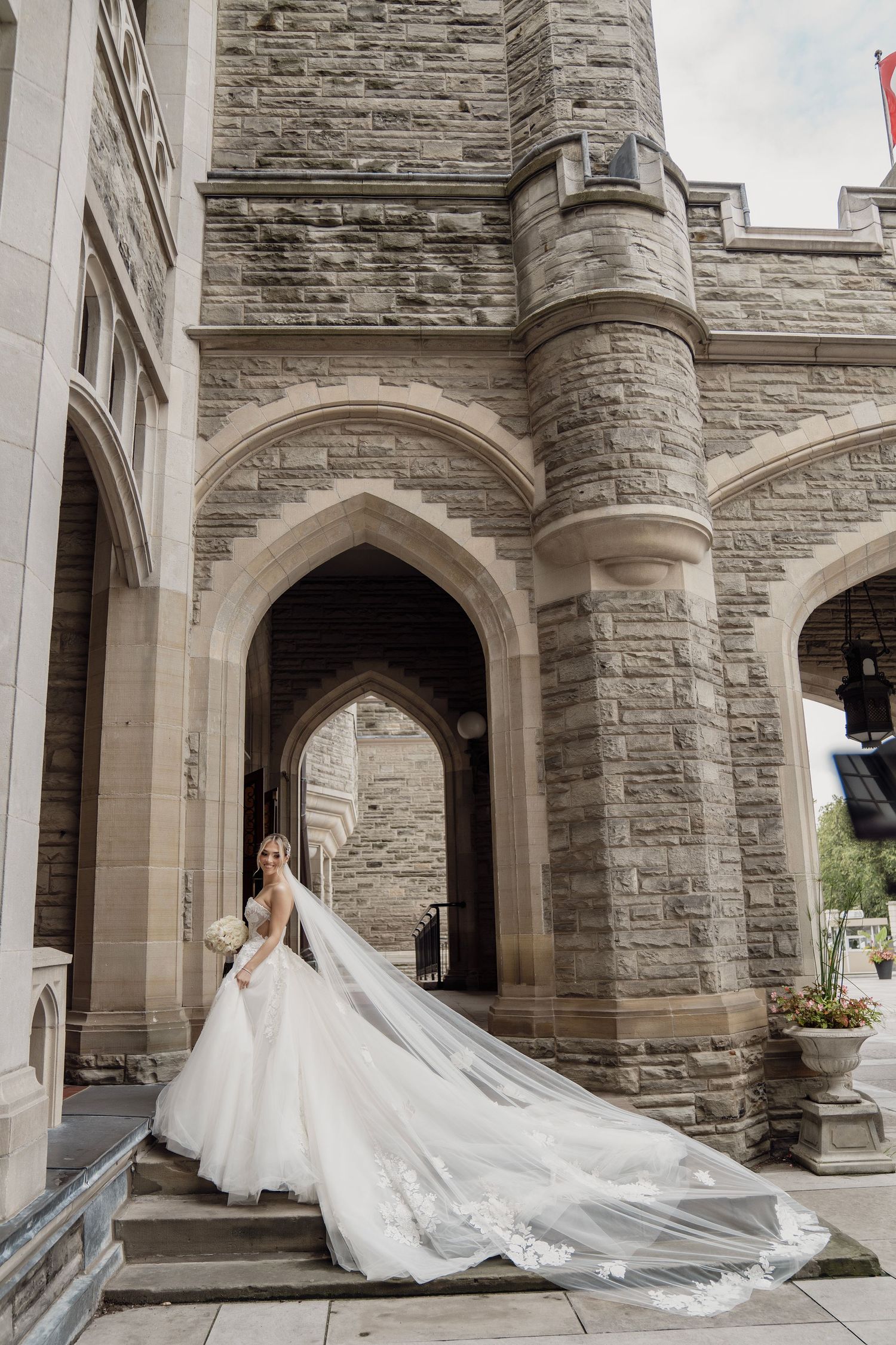 Dramatic cathedral wedding photos showcasing flowing train against stone gothic architecture.