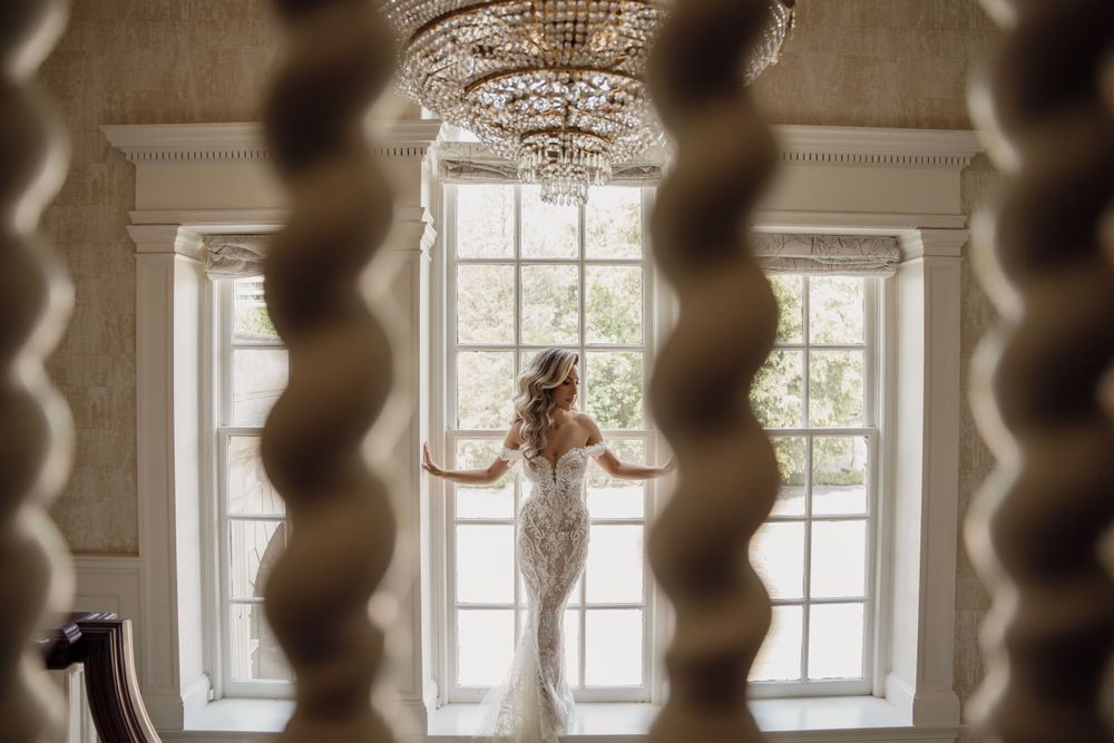 Silhouette view of bride through spiral staircase in elegant interior with chandelier.