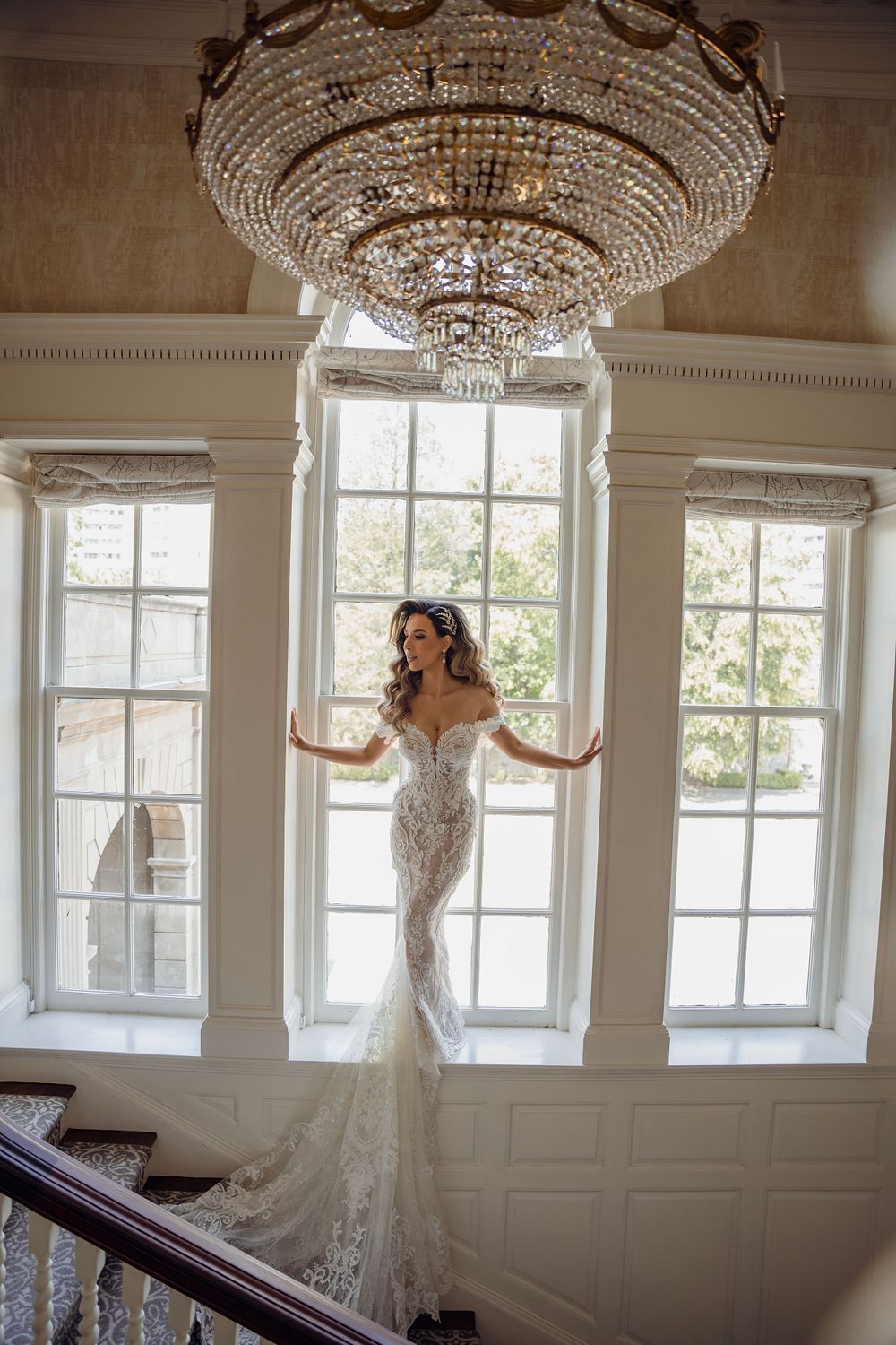 Elegant bridal portraits under ornate crystal chandeliers in a classic white room.