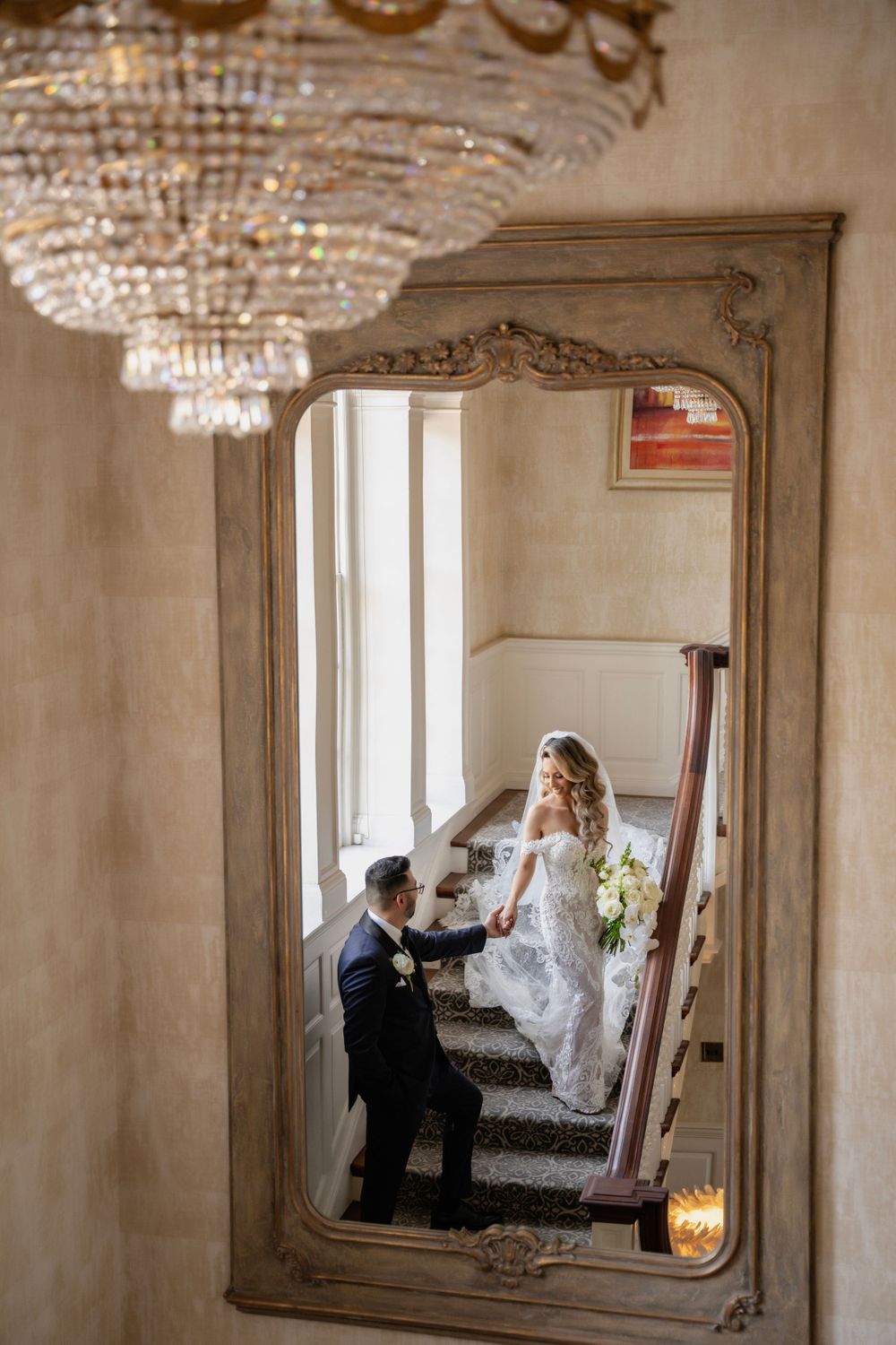 A vintage room with crystal chandelier and ornate mirror captures preparation moments through reflections.