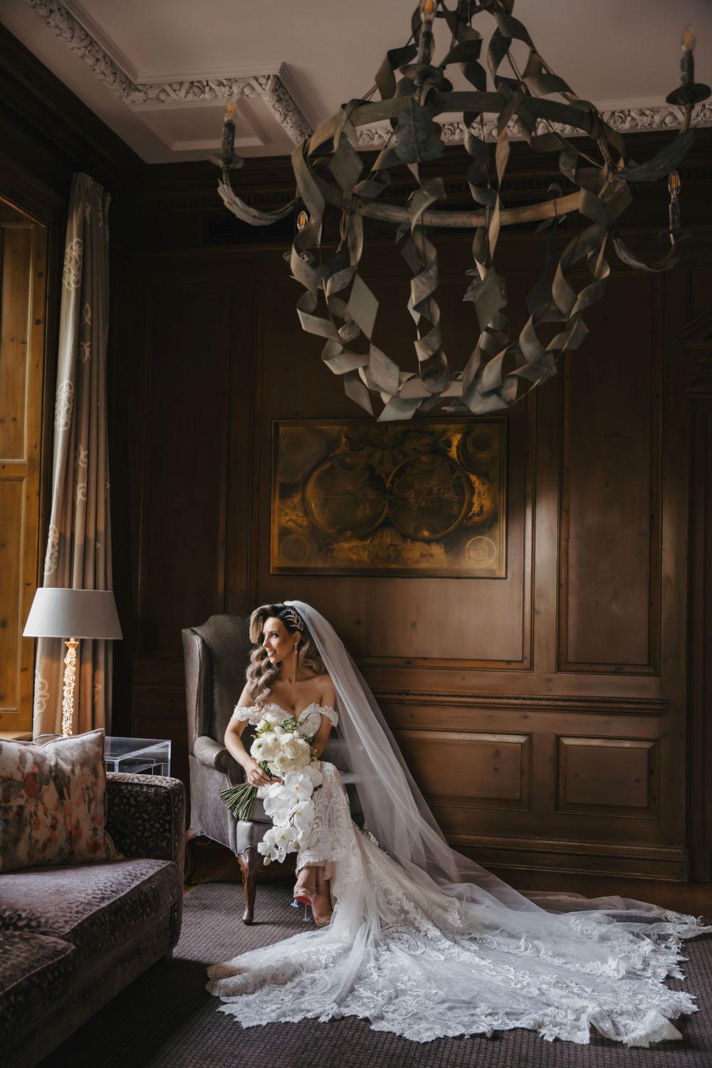 Ornate dark wood paneled room with dramatic bridal portrait and flowing lace train.
