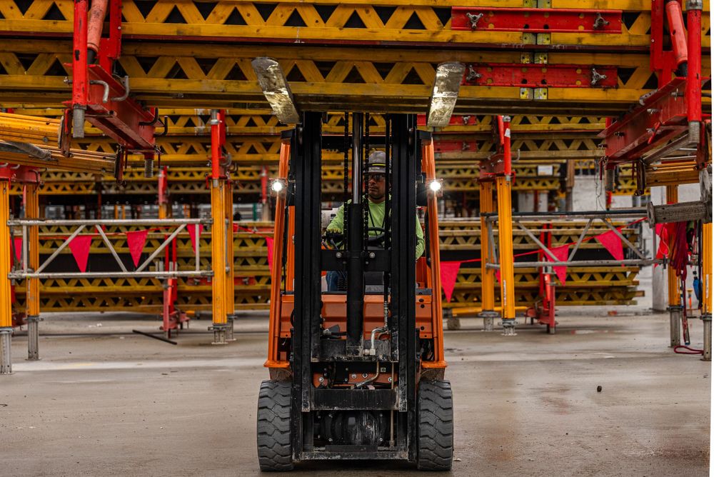 Industrial forklift positioned under yellow and red metal framework structure.