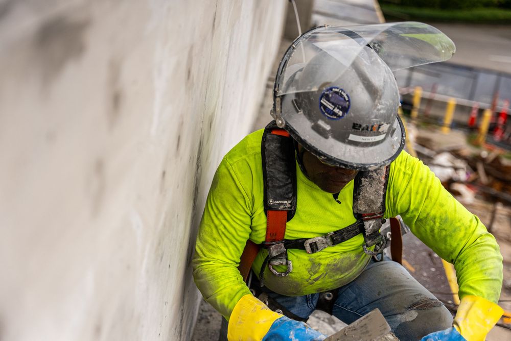 Construction worker in high-visibility gear performing safety inspection on building site.