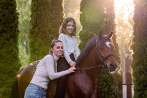 Mom and her daughter smiling towards the camera while the girl sits on her pony. Photo taken during a photoshoot in Dural Sydney