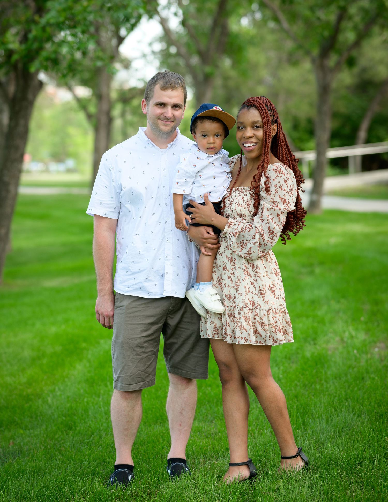 A casual family photo taken in a park setting on a sunny day.