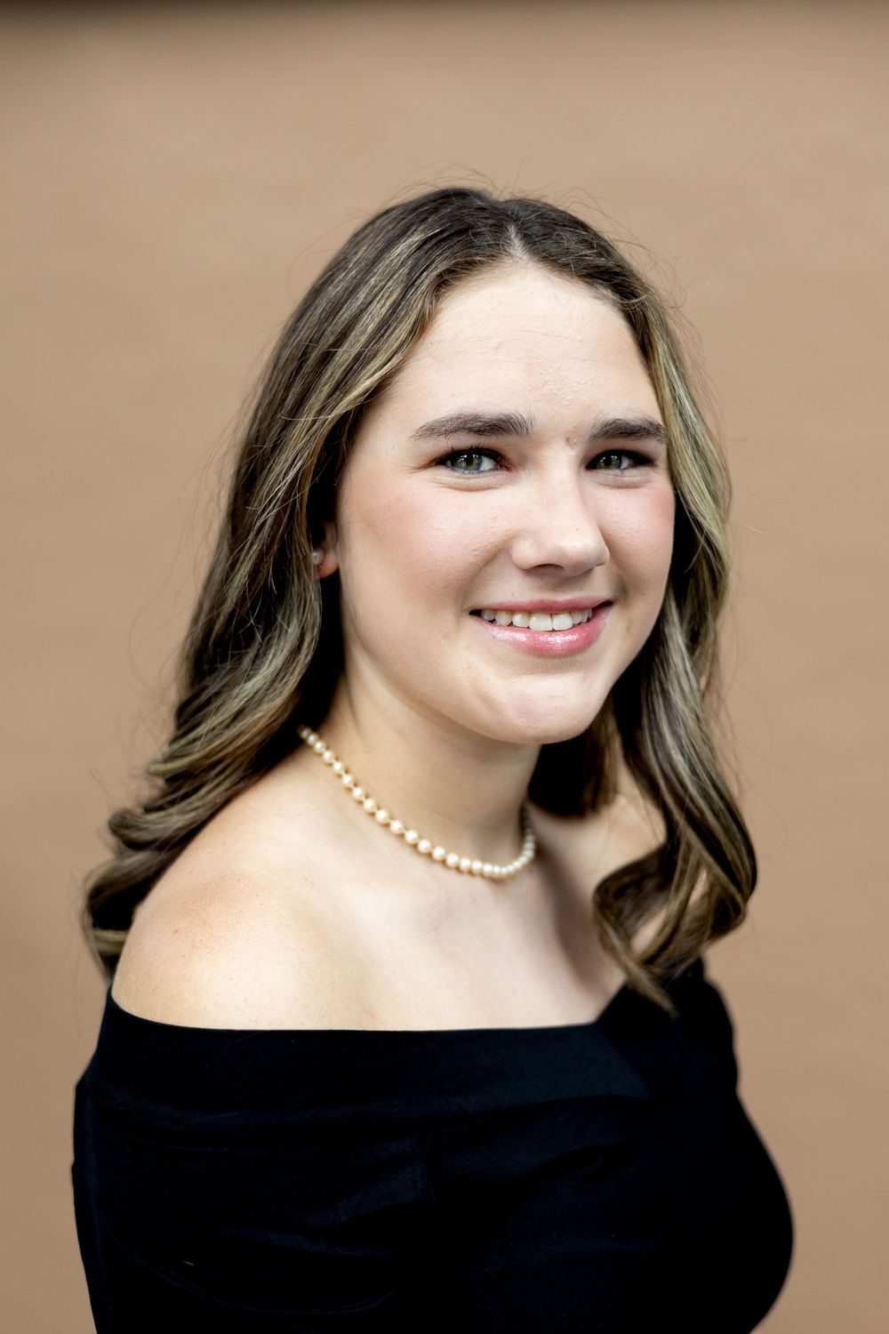 Portrait series showing different poses against a neutral beige background wearing a black top and pearl necklace.