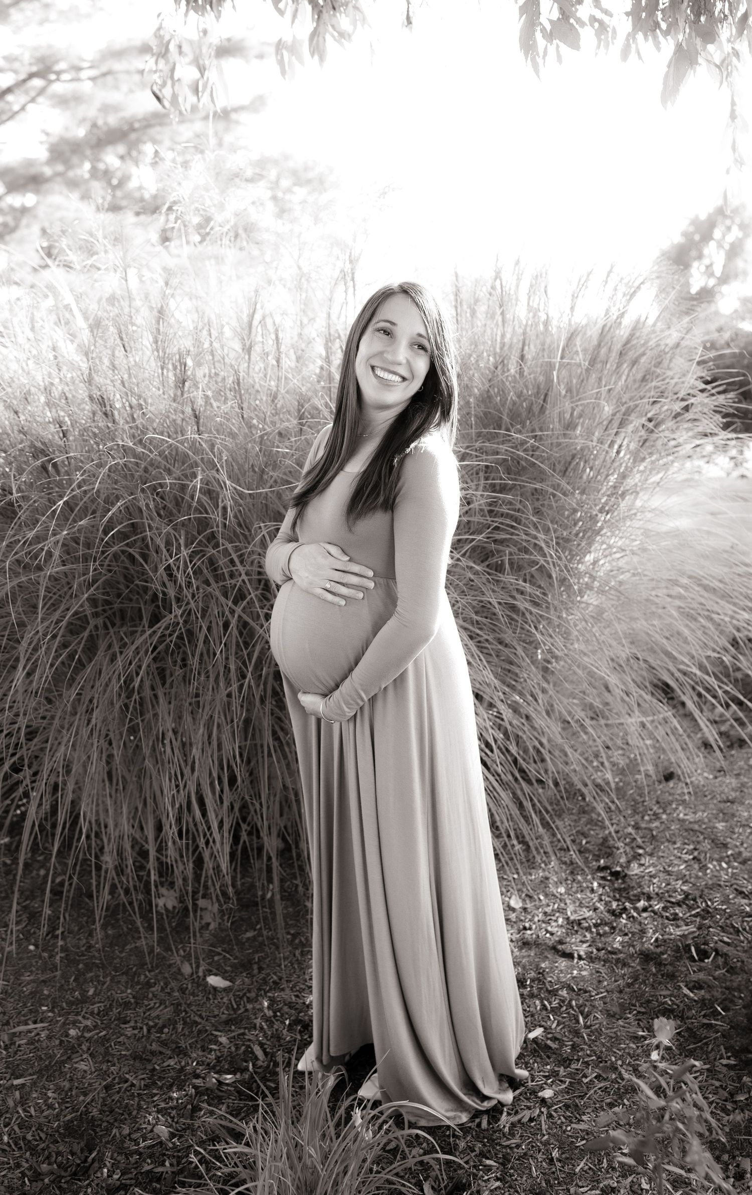 Black and white maternity portraits against natural grass backdrop.
