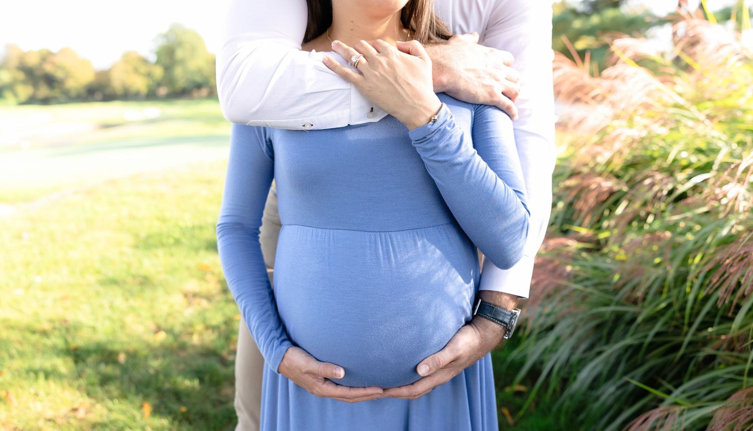Maternity photography session showcasing expecting mother in flowing blue dress outdoors.