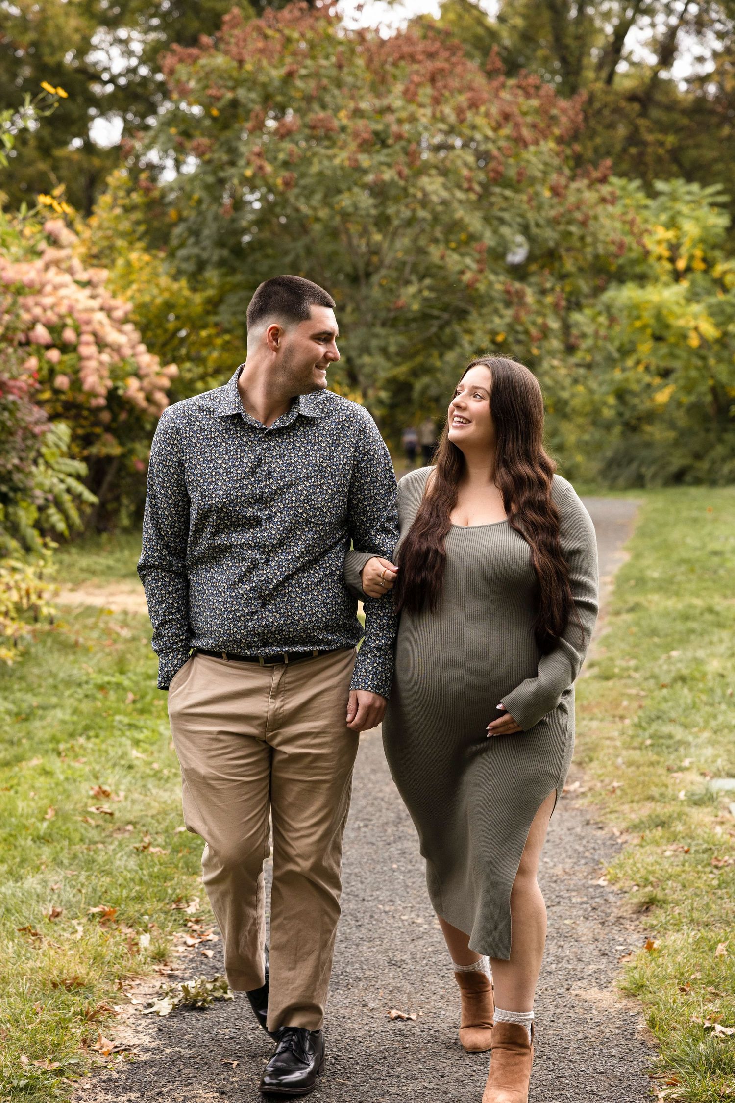 Couple walking together on an autumn path surrounded by colorful fall foliage.