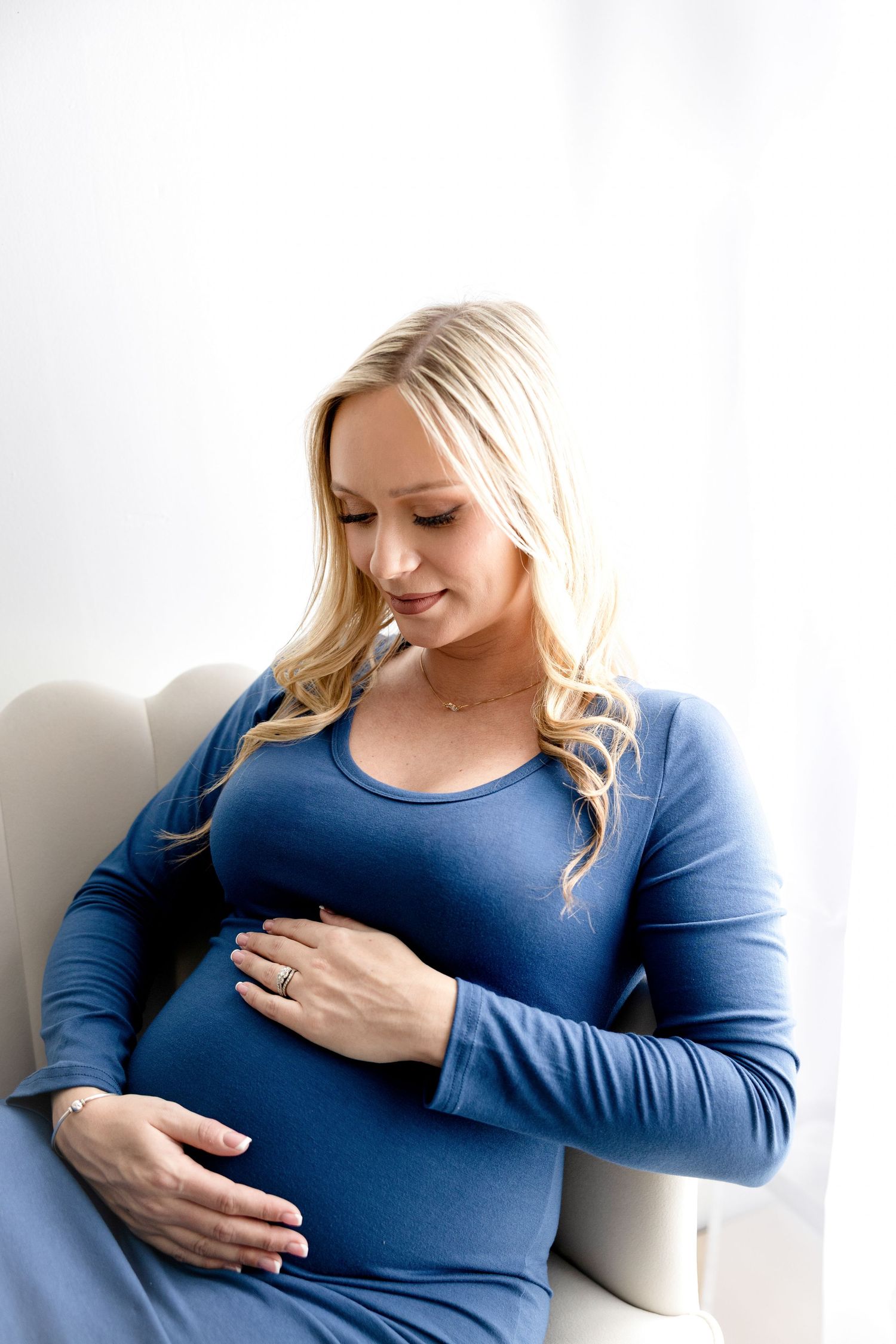 Maternity portraits featuring woman in blue dress cradling baby bump.