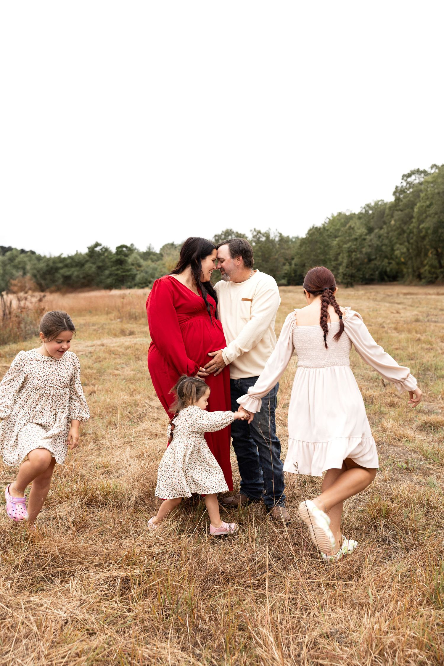 Family playing and running together in a golden field during sunset.