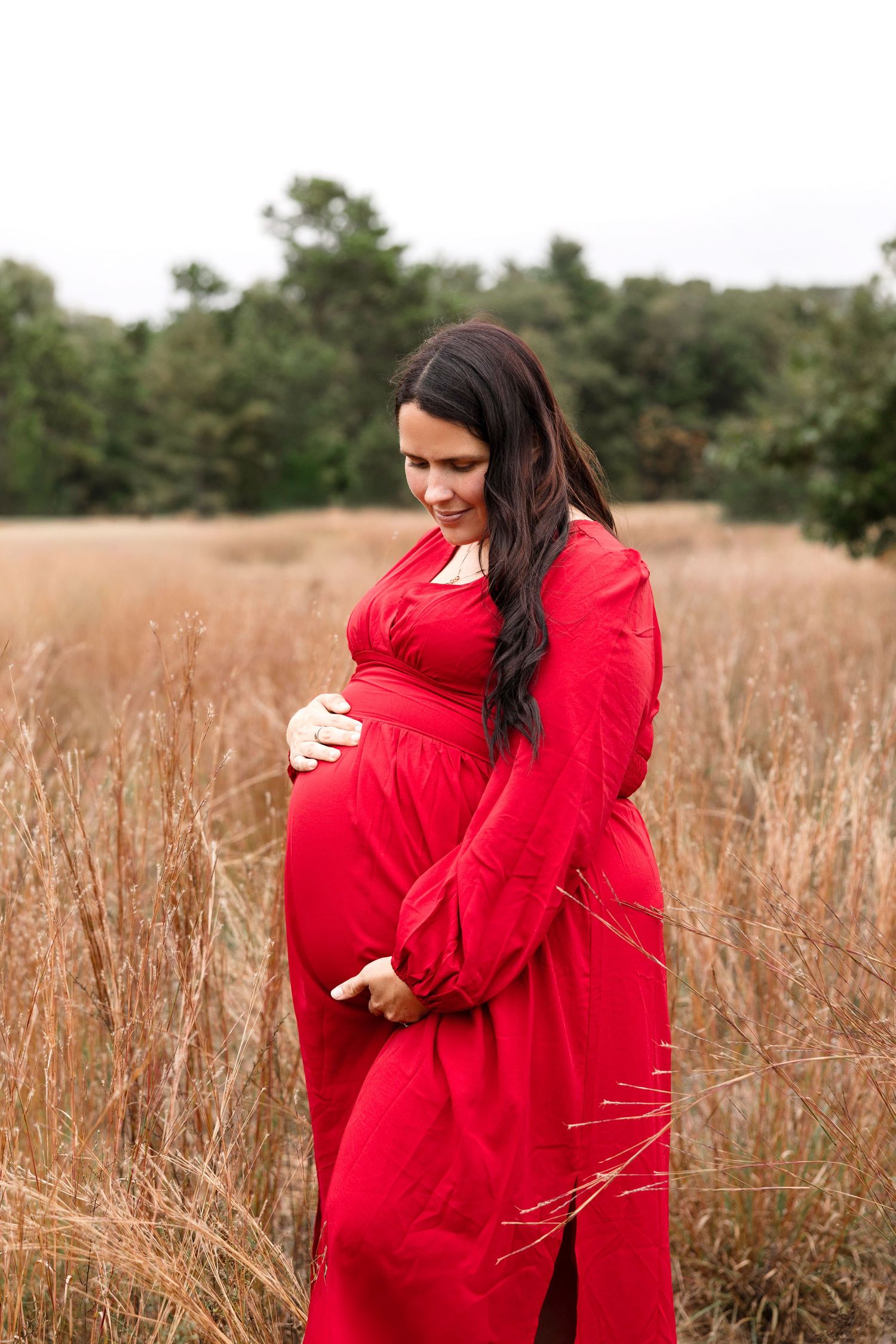 Person in bright red sweater standing in tall autumn grass field.