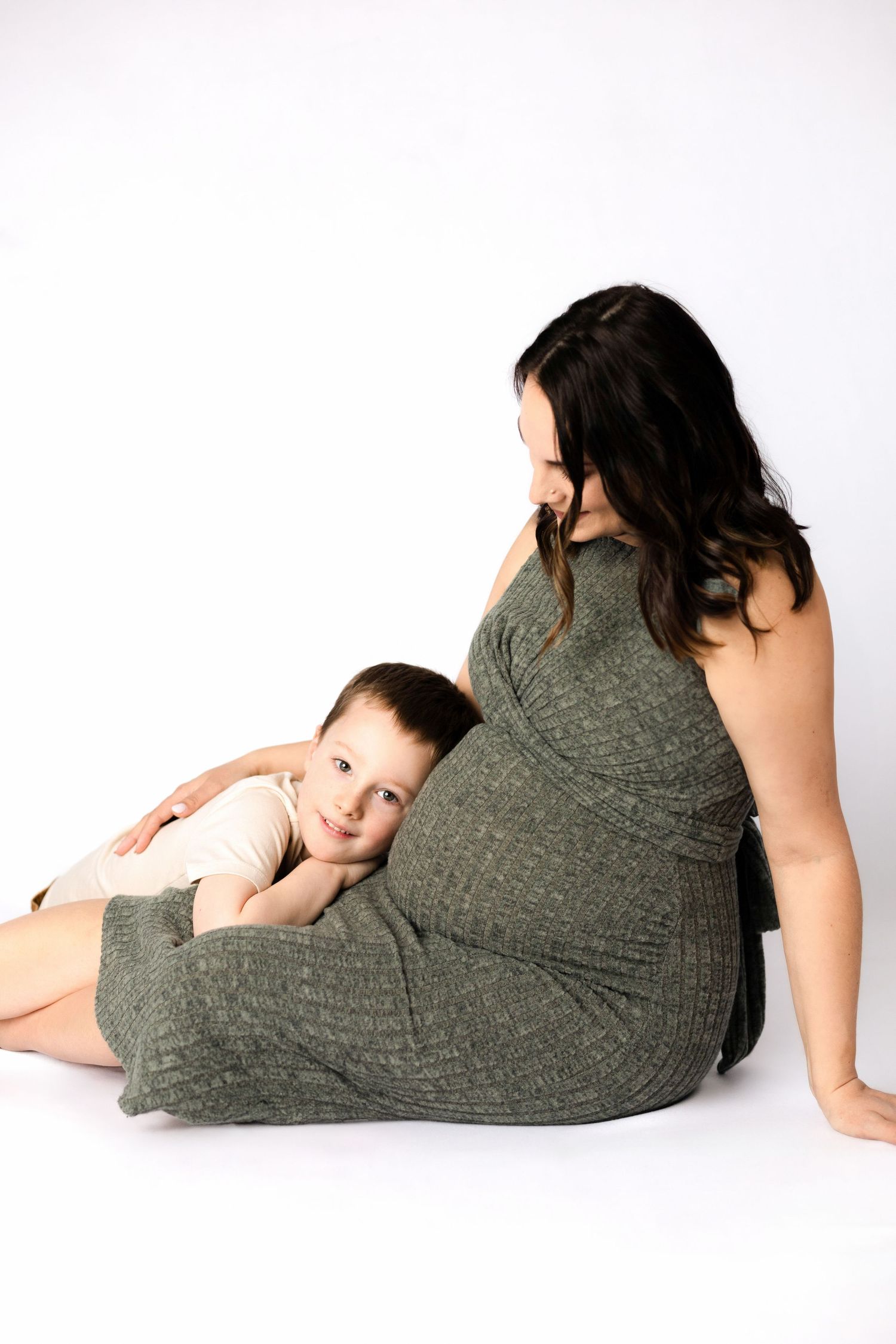 Mother and child in grey dress laying down together in studio setting.