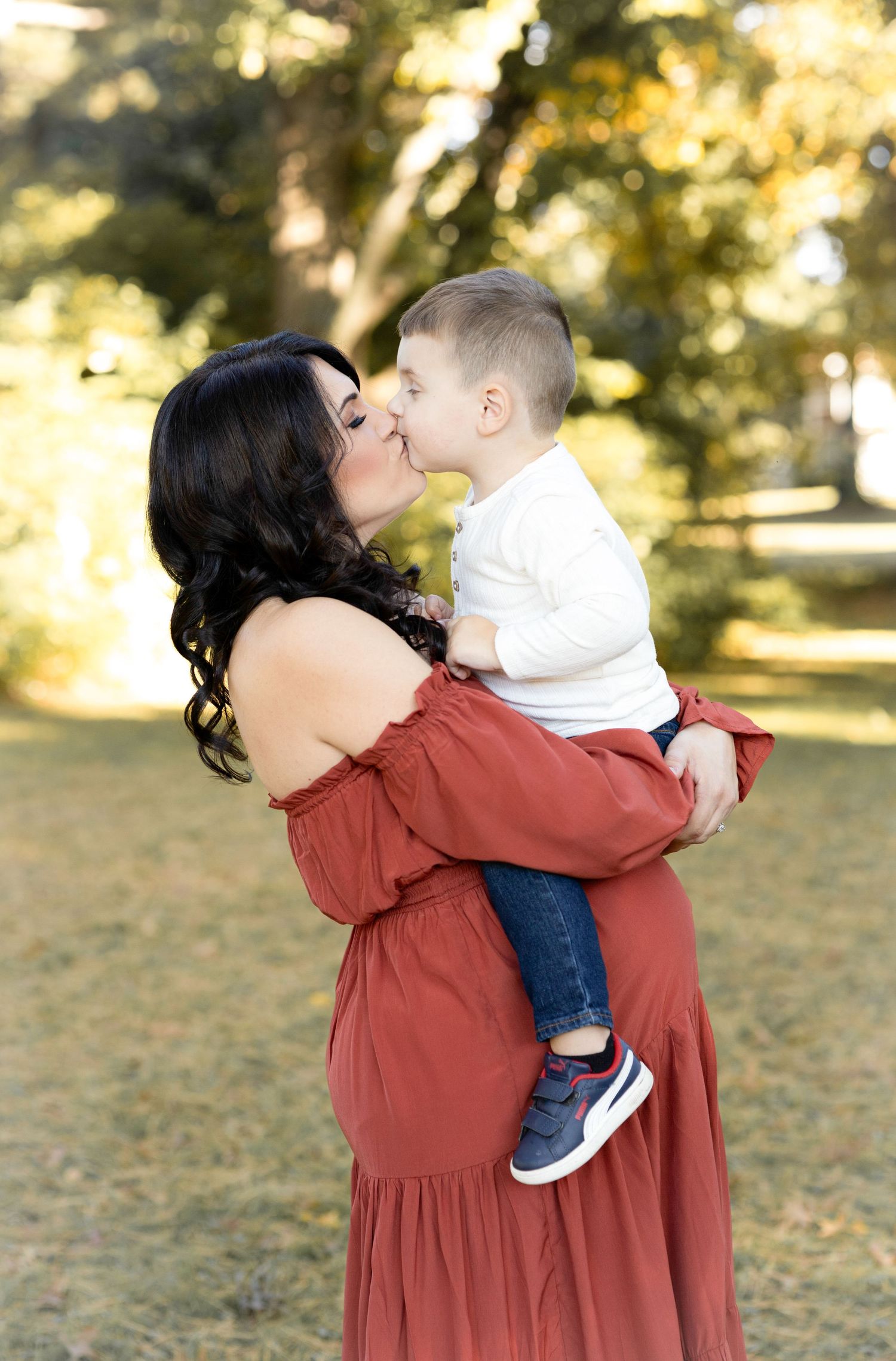 A tender moment captured between family members in a rustic outdoor setting with fall foliage.