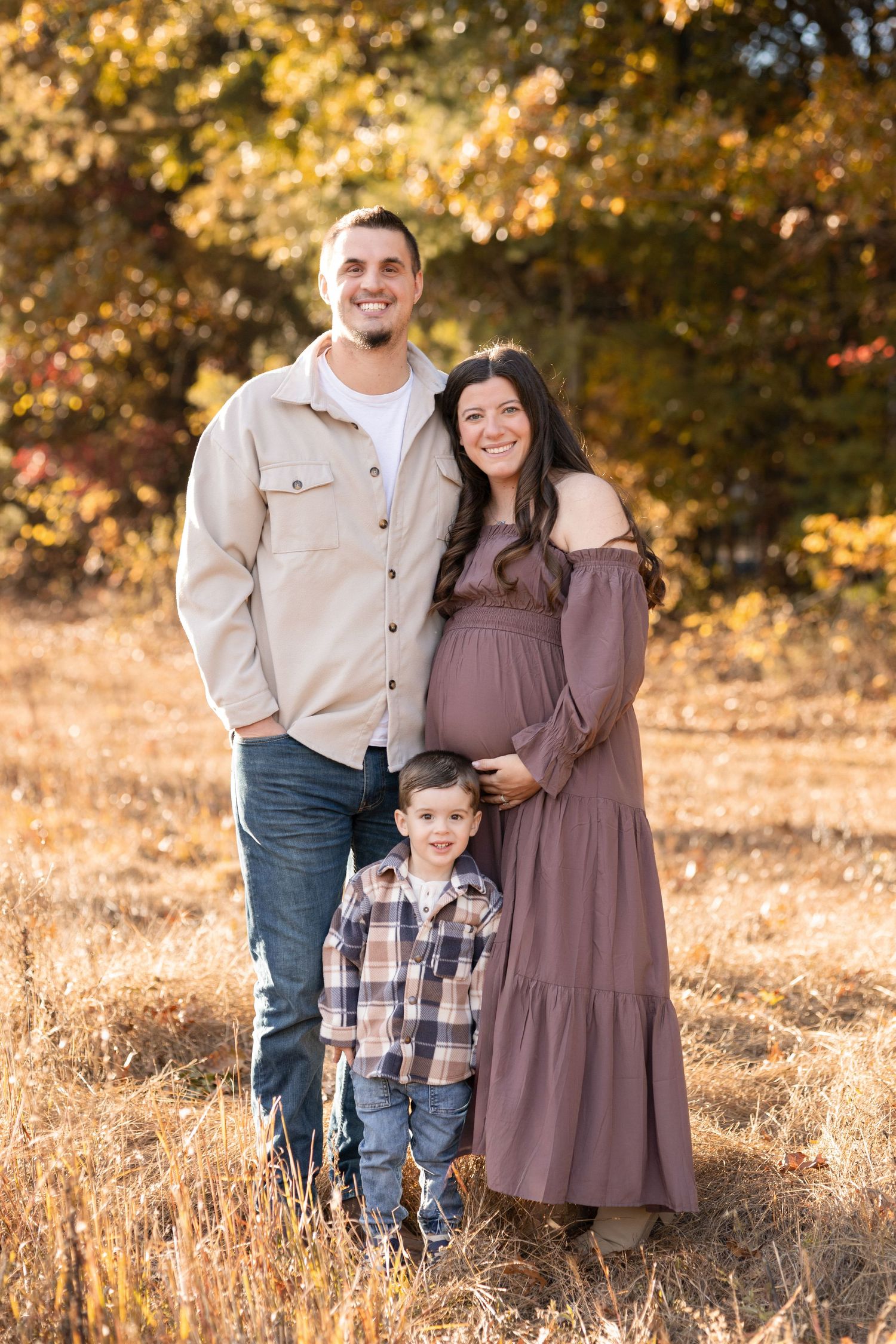 Family portrait session in a field with warm autumn colors and golden sunlight.