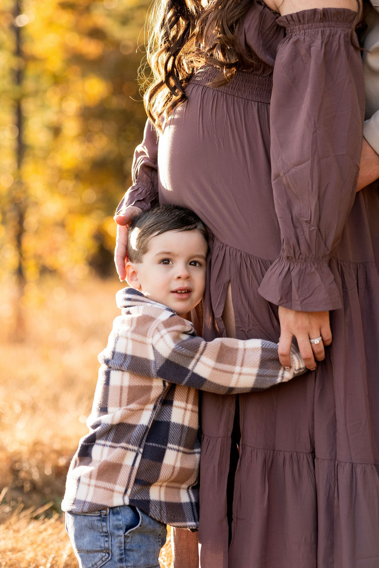 A close-up family moment captured in warm autumn light with natural outdoor scenery.