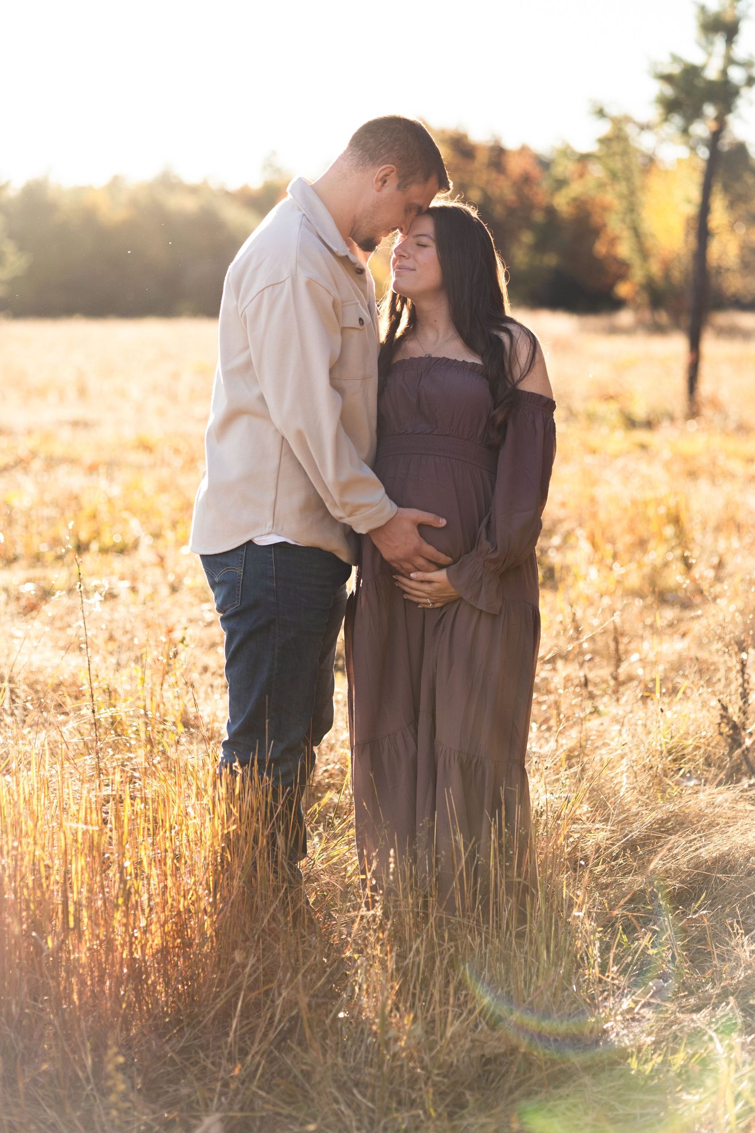 Intimate family moments captured in golden hour light among tall grass.