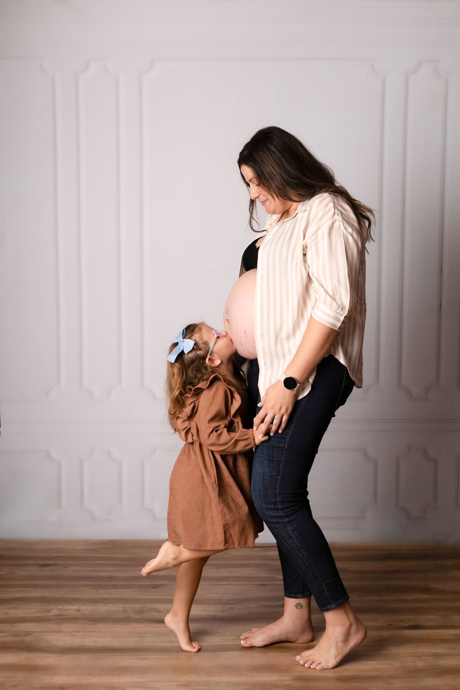 Sequence of intimate mother-child dance moments on wooden floor against white wall.