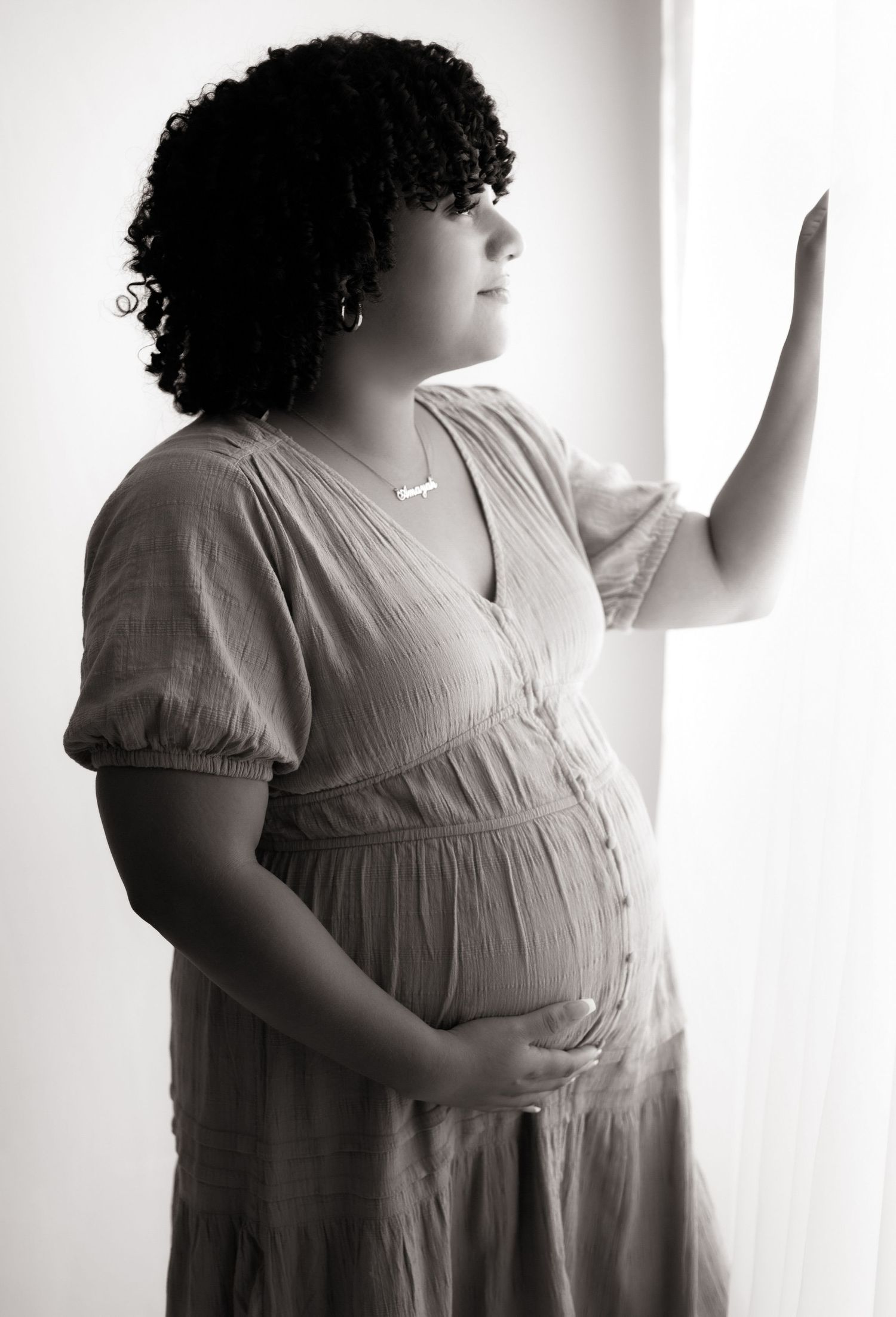 Black and white artistic maternity photos showing silhouette against bright window.