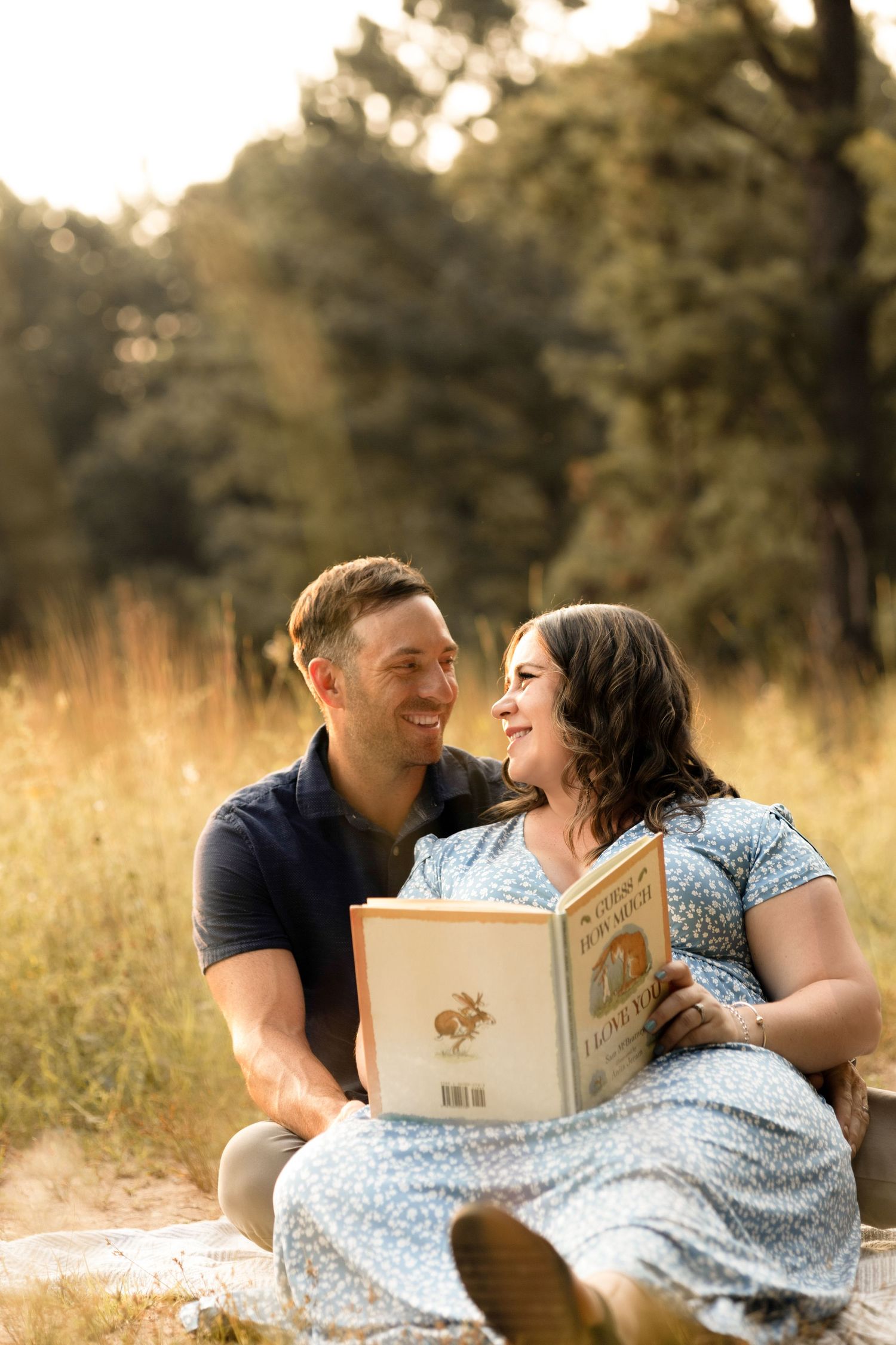 Couple shares intimate moment while reading book together in golden sunlit field.