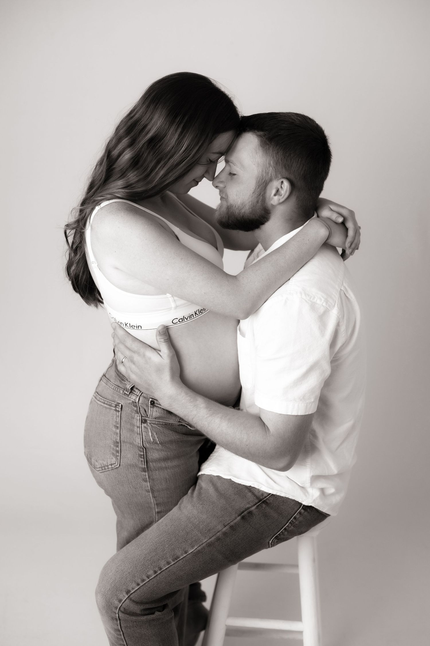 Black and white intimate couples photoshoot with dramatic poses against white backdrop.