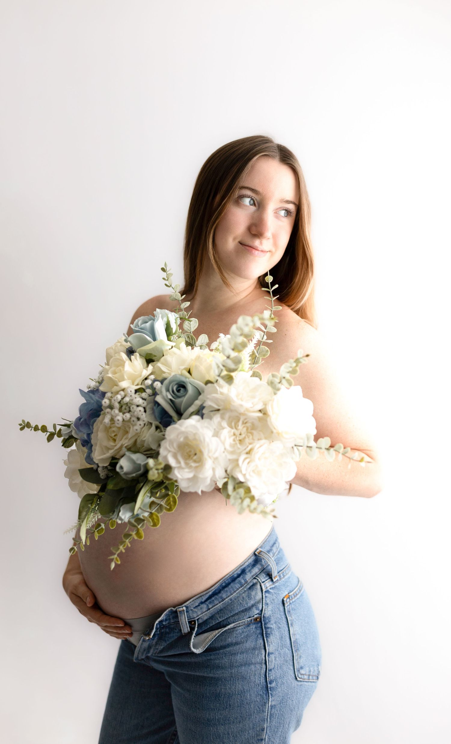 Maternity photos featuring woman holding beautiful white and blue floral bouquet.