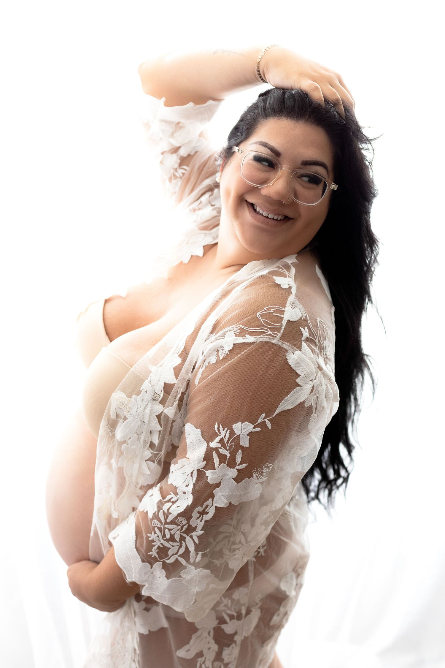 Artistic maternity photo featuring sheer lace overlay and soft lighting.