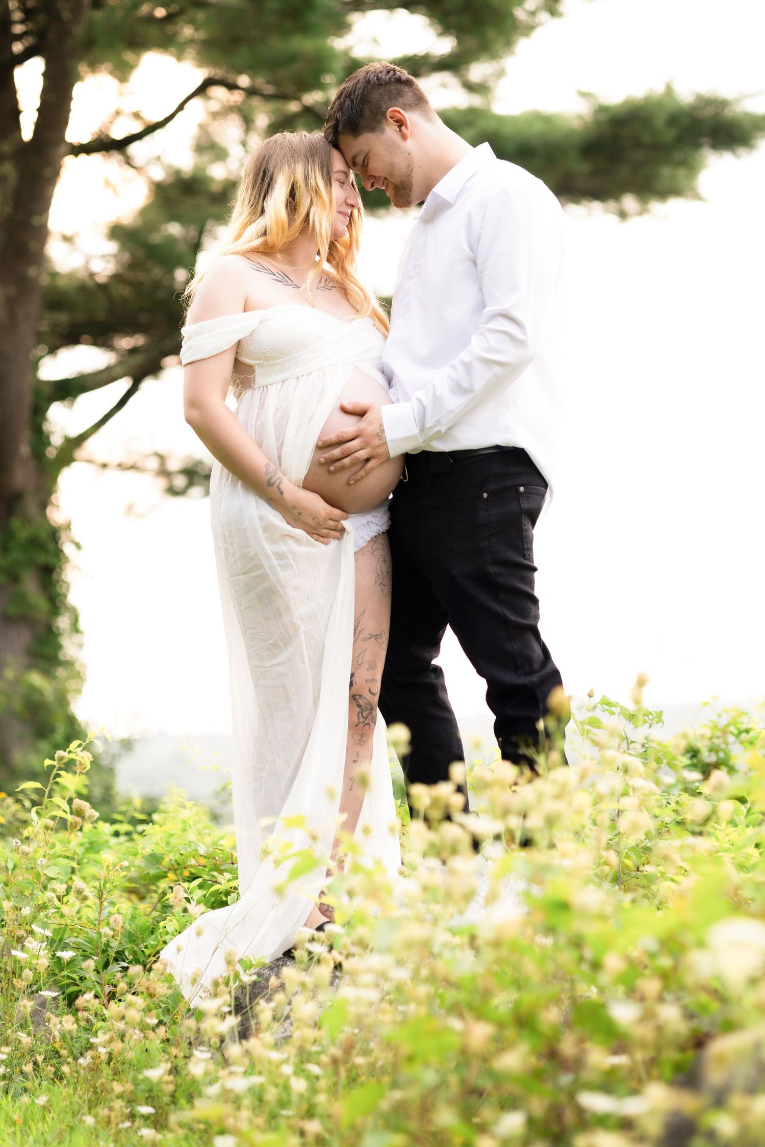 Couple in formal attire dancing among wildflowers in natural setting.