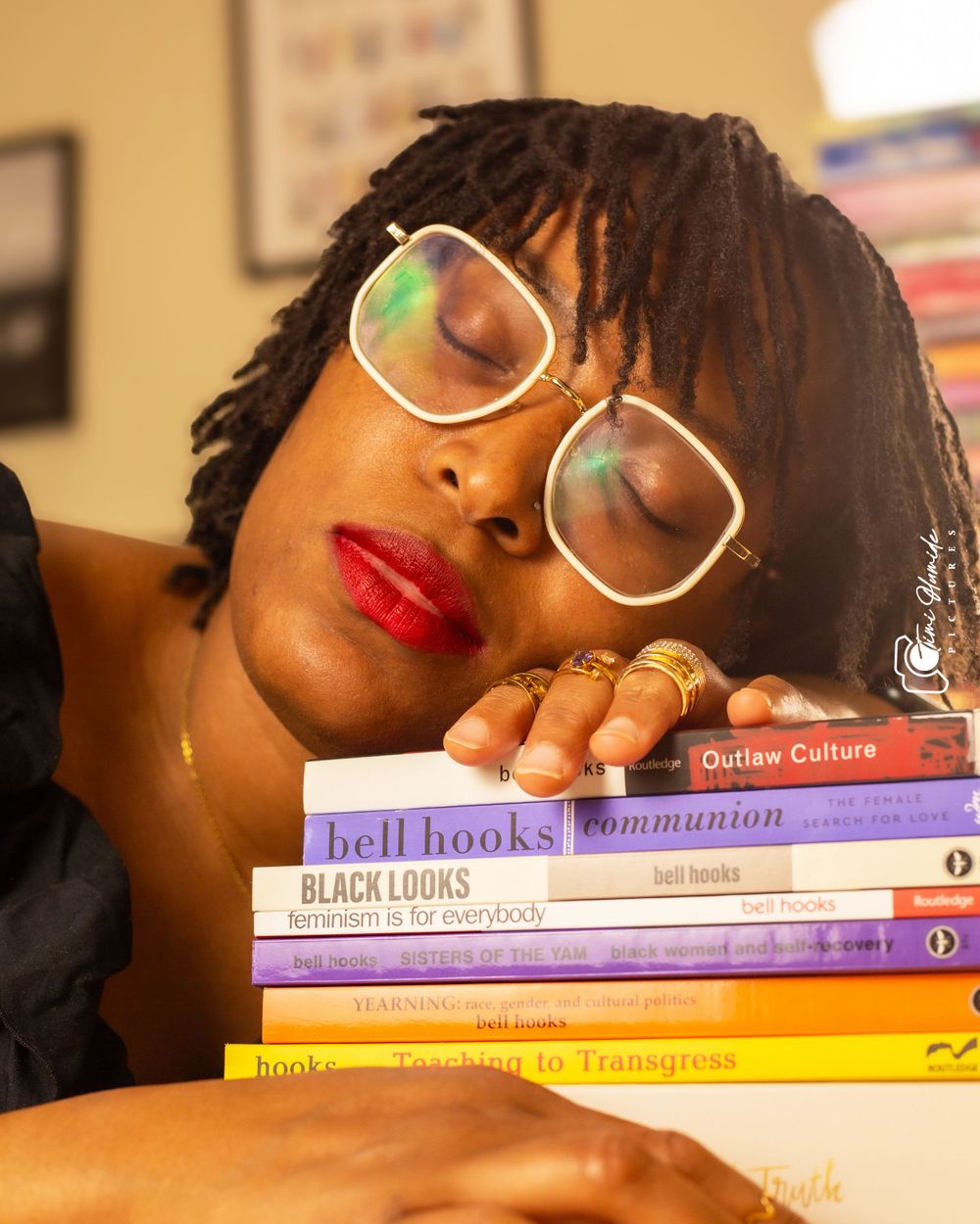 A person with dreadlocks and red lipstick poses with bell hooks literature.