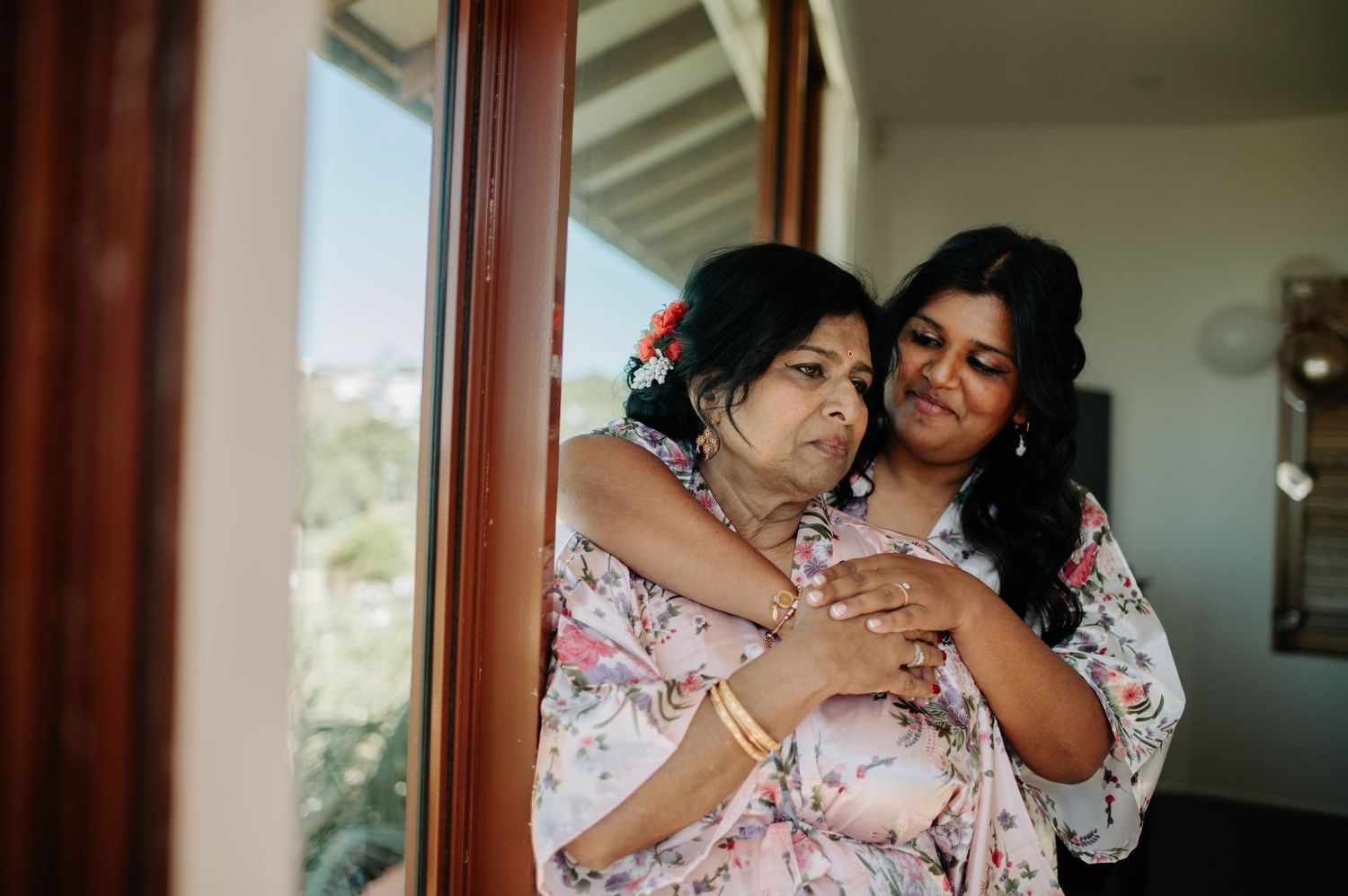 Emotional embrace between two people wearing matching floral robes.