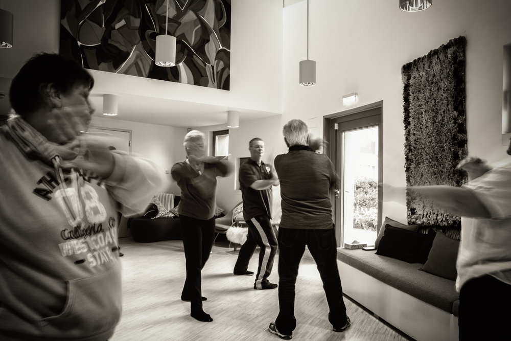 A black and white photo shows people participating in a group exercise class in a modern interior space.