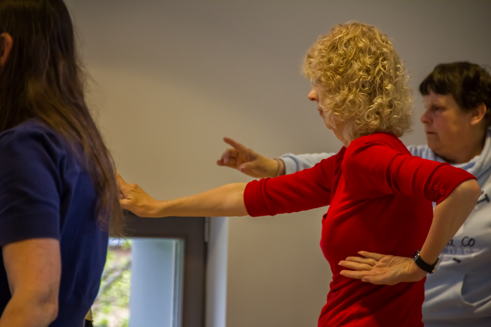 Participants in a dance class practicing movements with arms extended.