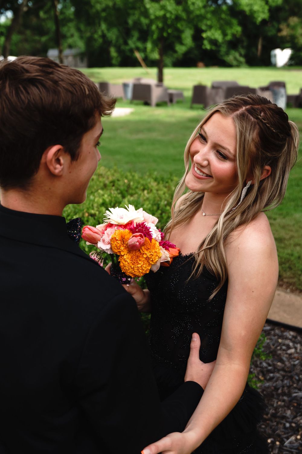 Couple shares a romantic moment with colorful flowers in a garden setting.