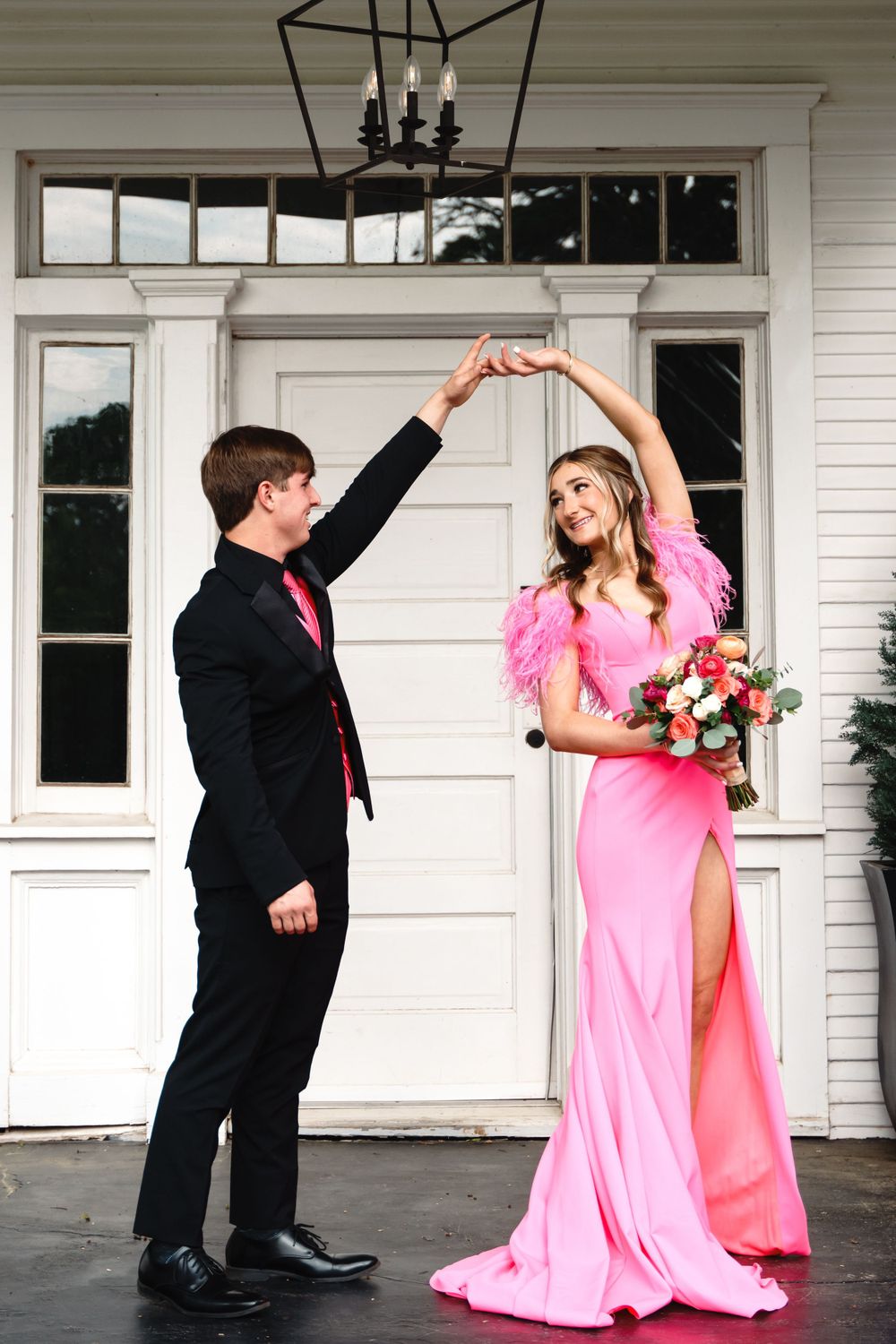 Couple in formal wear dancing, with her pink gown flowing elegantly against white backdrop.